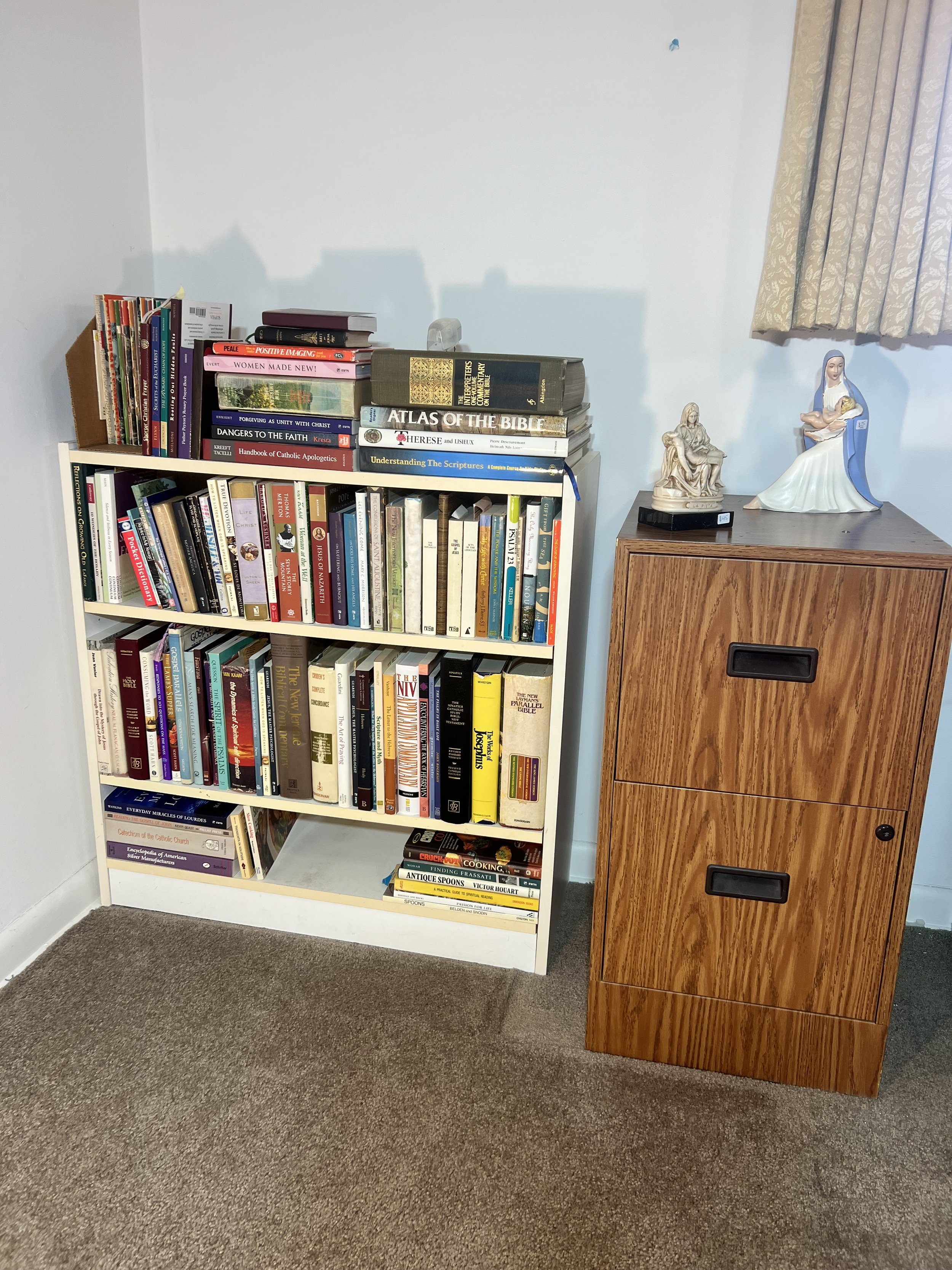 White bookcase filled with an extensive collection of Christian theology and biblical reference books
