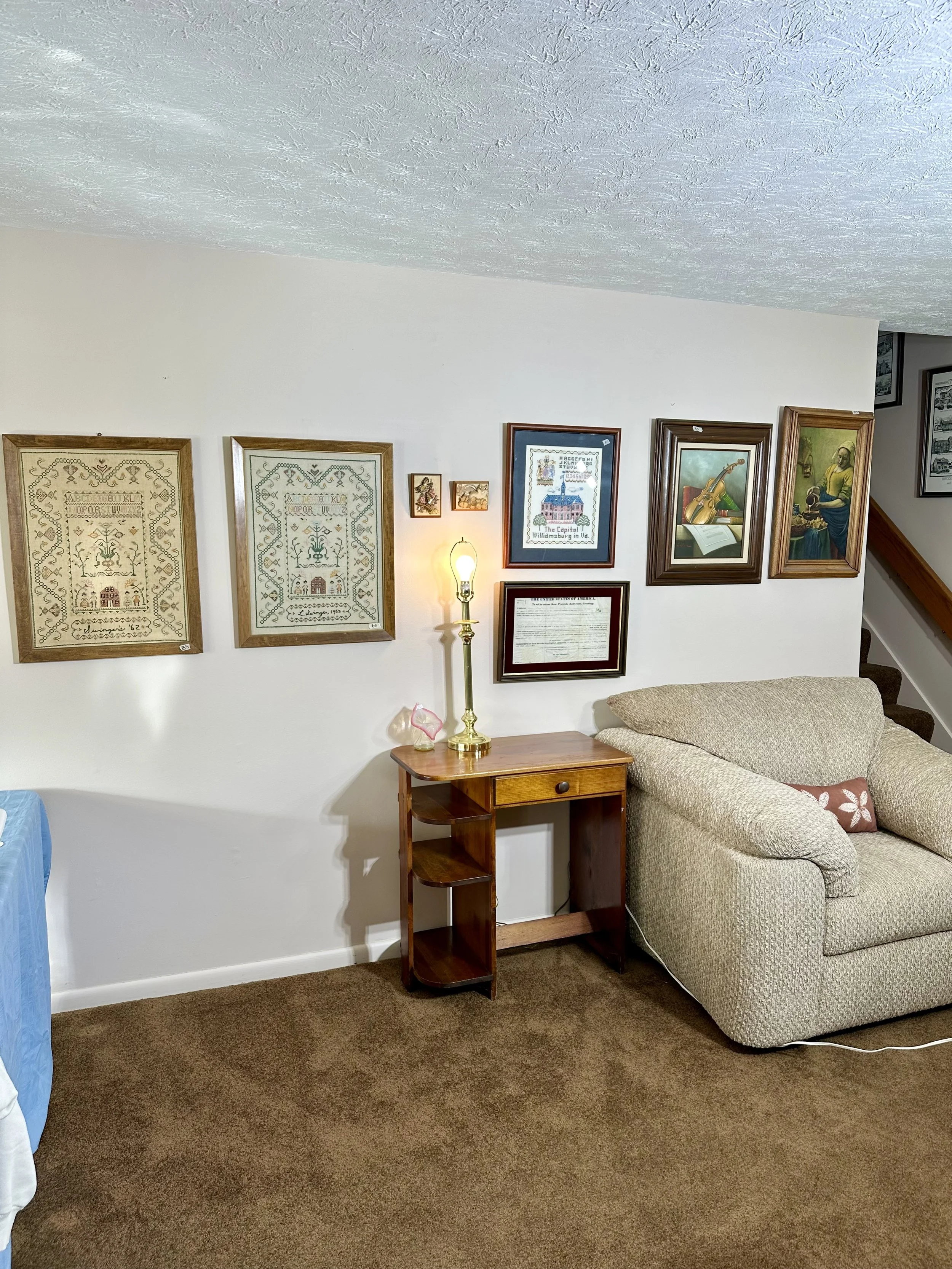 cross-stitch framed art, deco style wooden side desk, large oversized chair