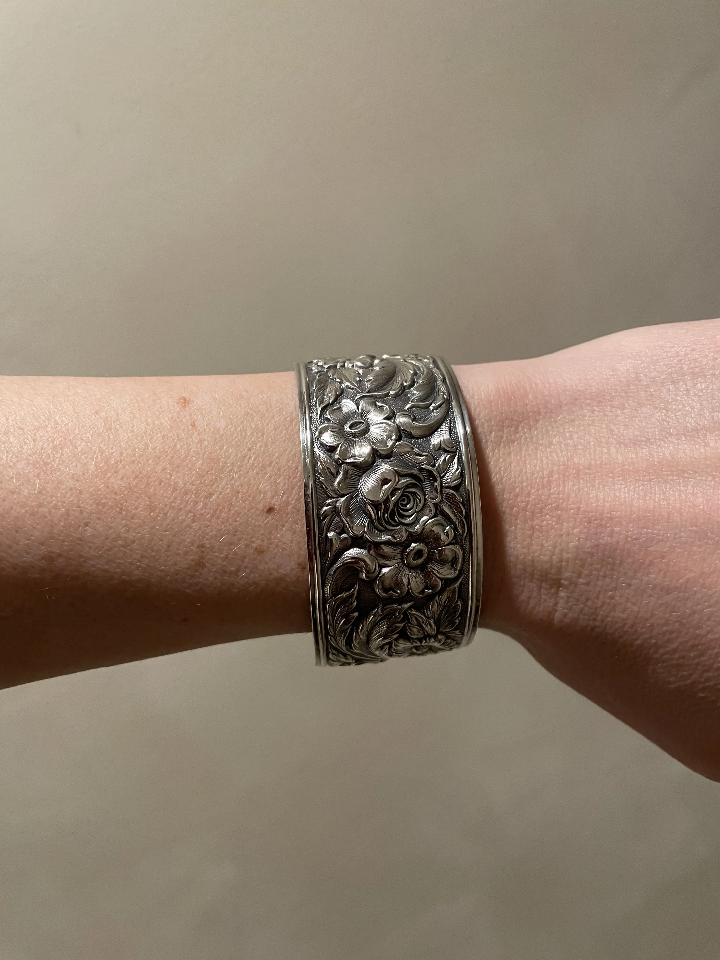 A stunning vintage sterling silver wide-band cuff bracelet featuring a deeply embossed, high-relief rose and floral pattern