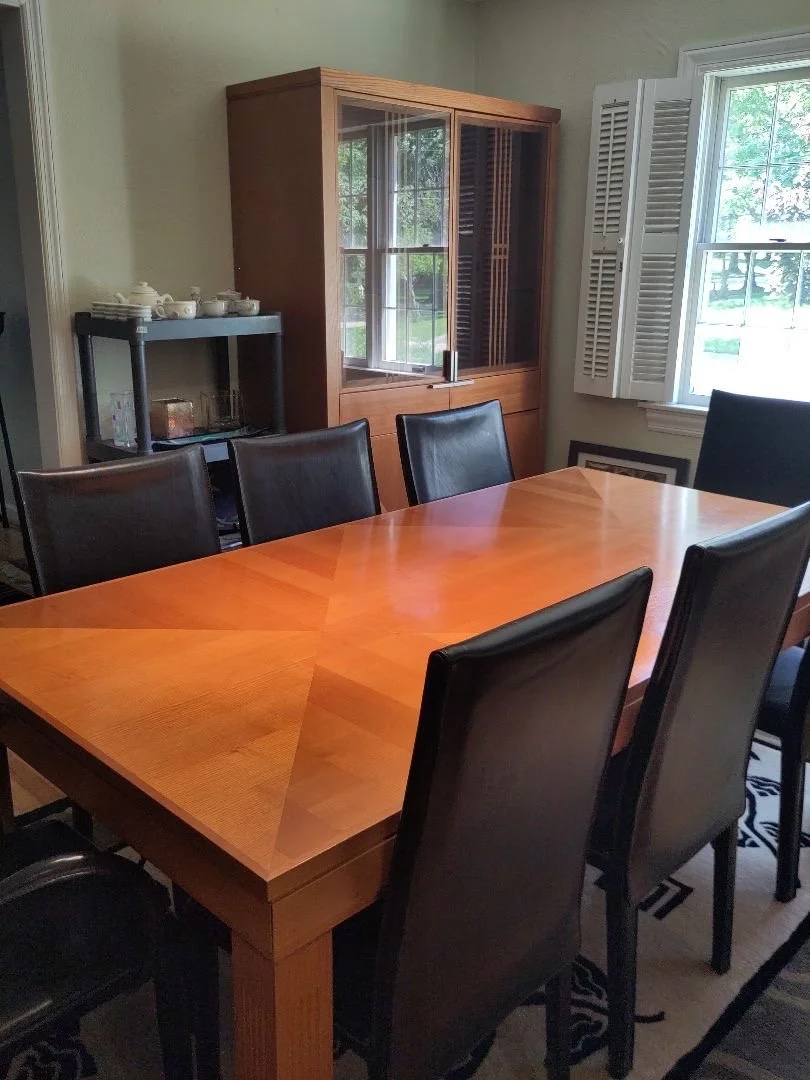 Designer wood dining table showcasing a starburst veneer top, matching tall hutch.