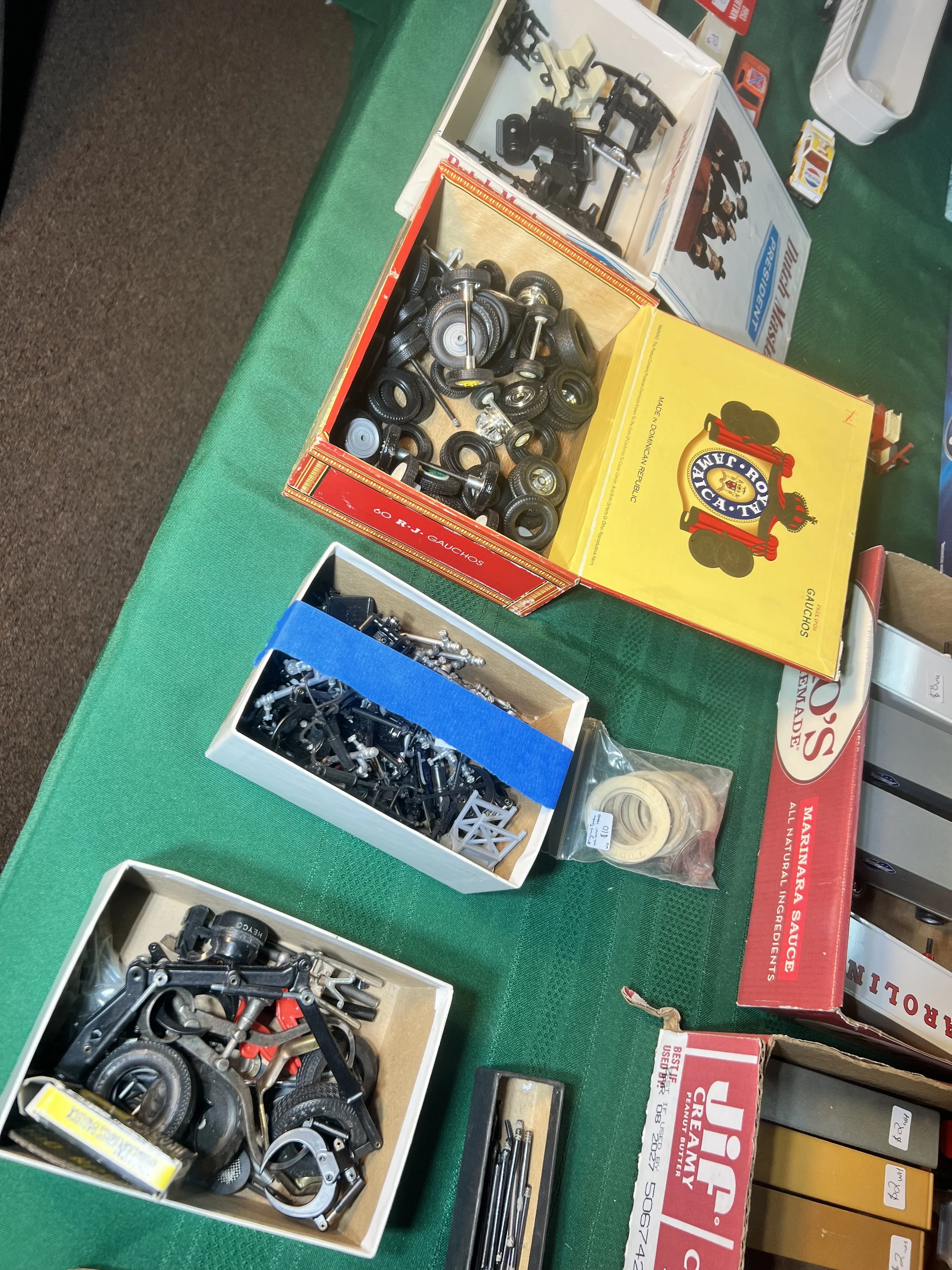 Boxes filled with vintage metal axles and rubber tires for model restoration