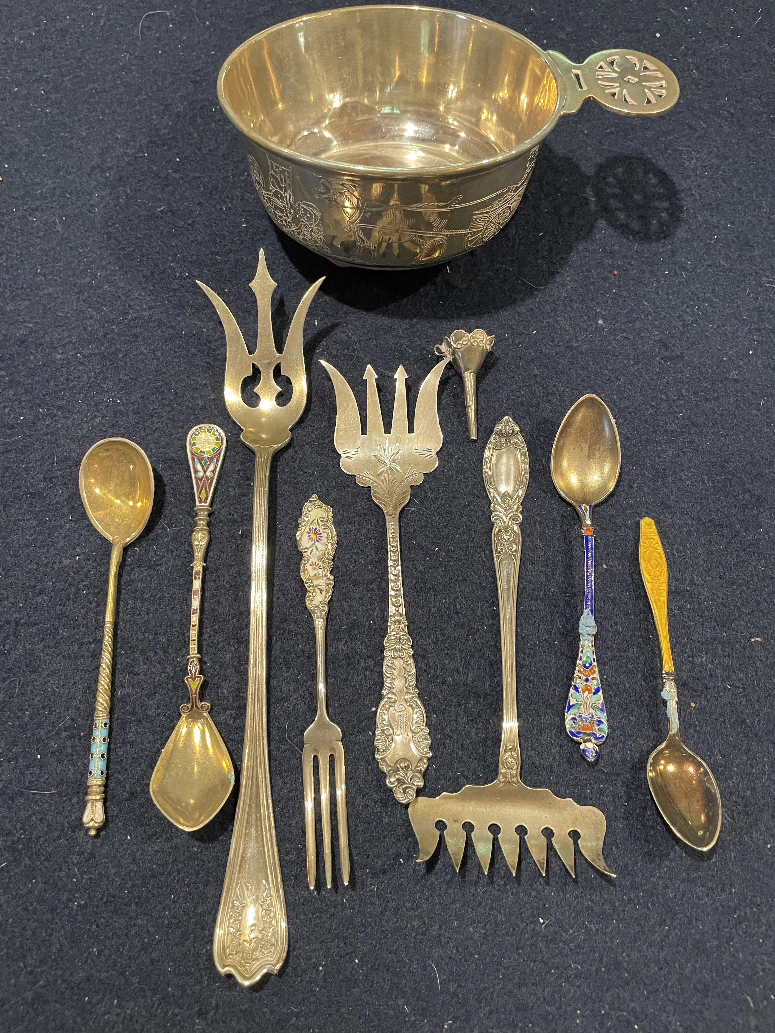 An exceptional collection of antique specialty silver featuring a large embossed presentation bowl, ornate cold meat forks, and exquisite enamel-handled demitasse spoons