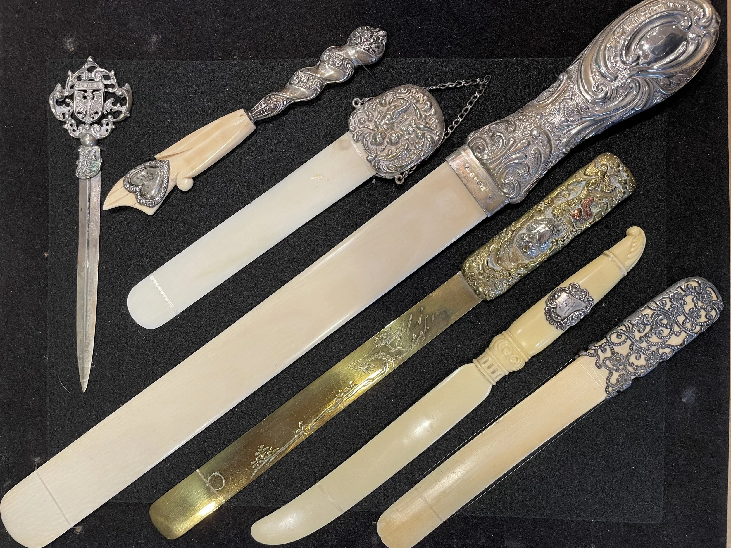 An exceptional collection of antique letter openers and page turners featuring sterling silver handles, carved bone, and etched brass blades