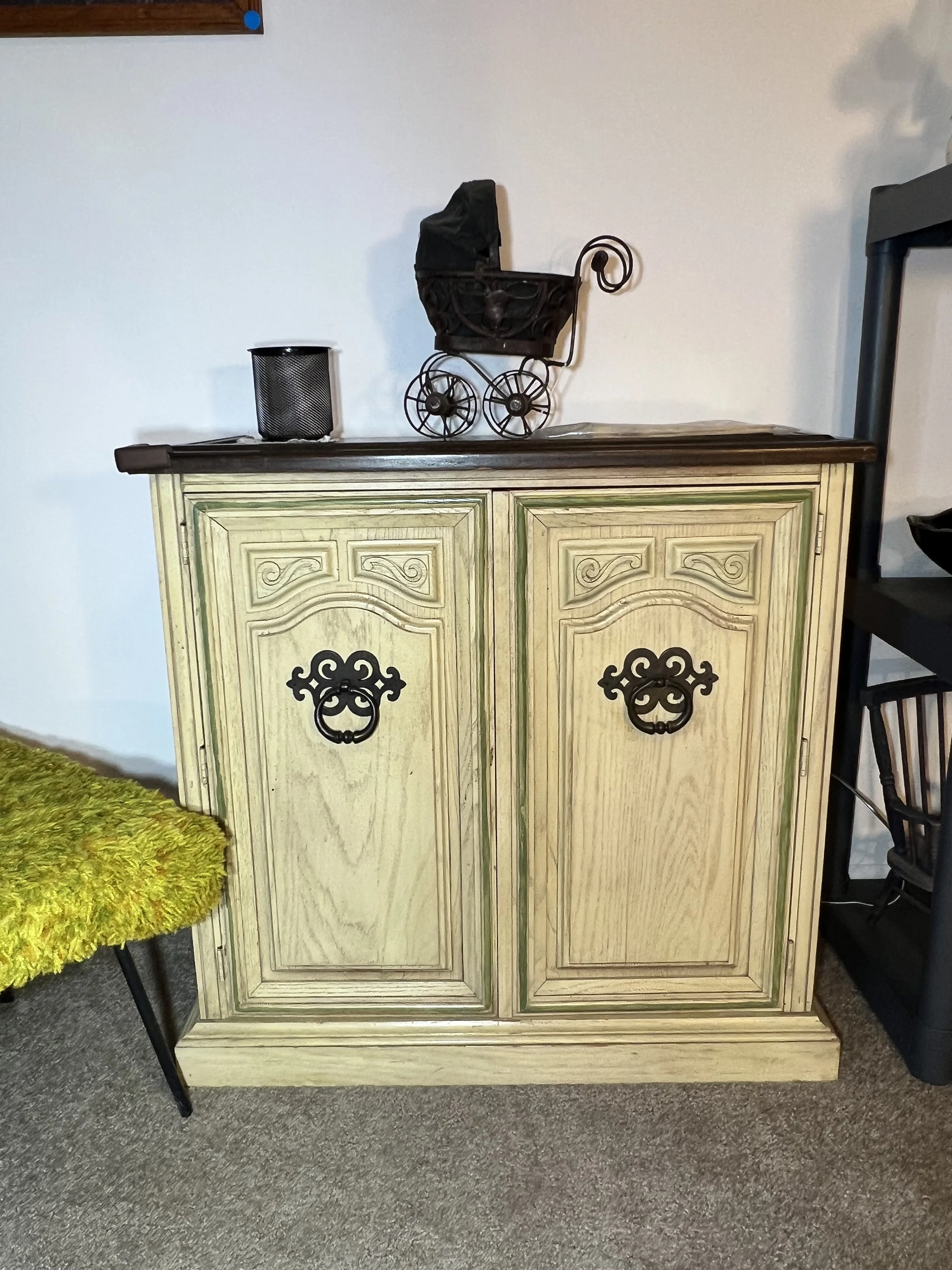 Elegant cream-colored French Country cabinet with ornate dark hardware