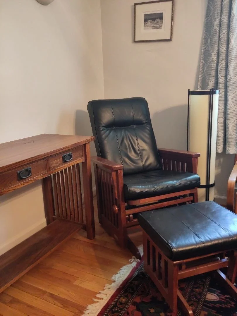A black leather glider chair and floor lamp