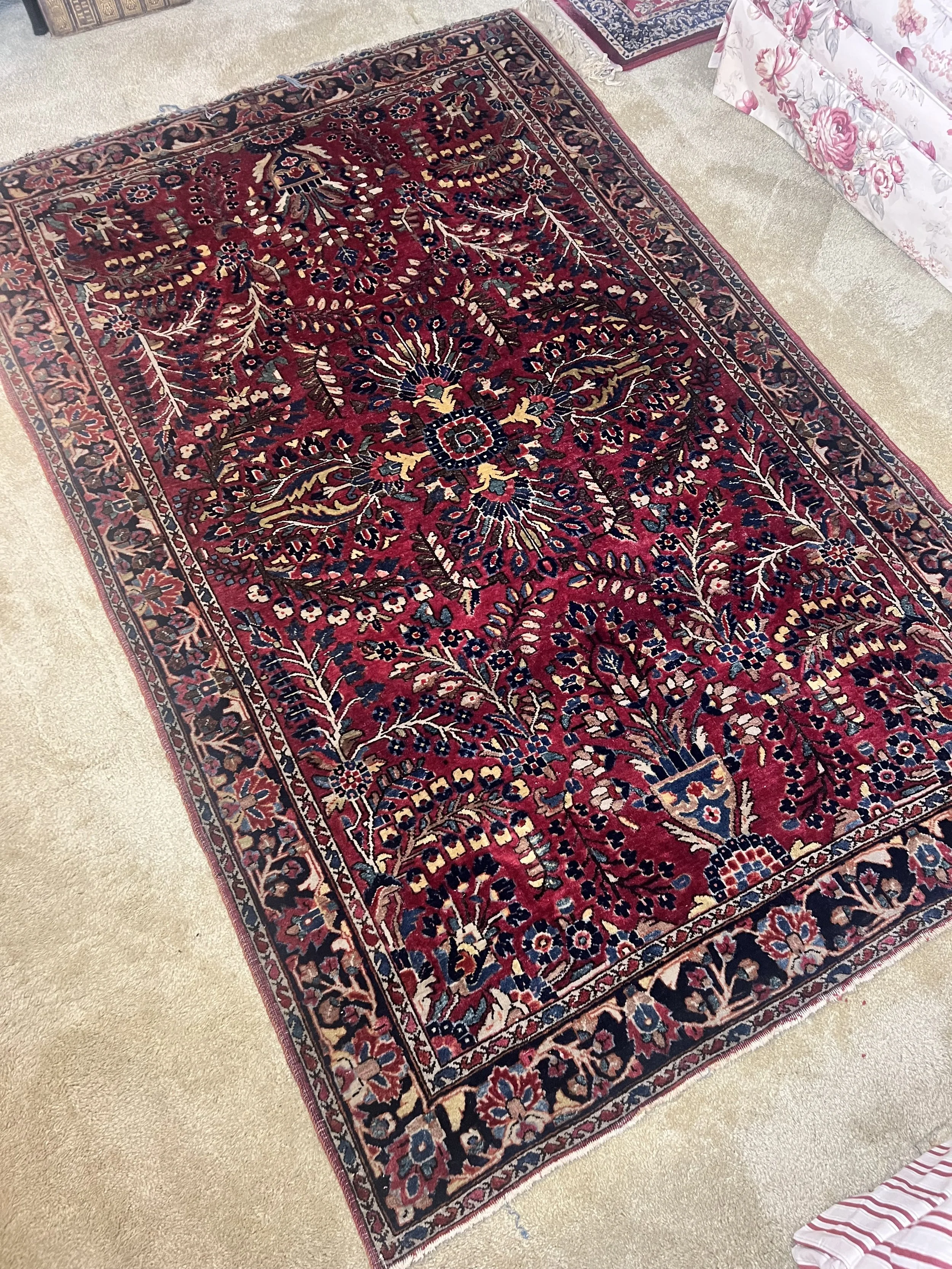 A beautiful hand-knotted wool area rug featuring a vibrant red field with intricate floral "Tree of Life" and medallion patterns