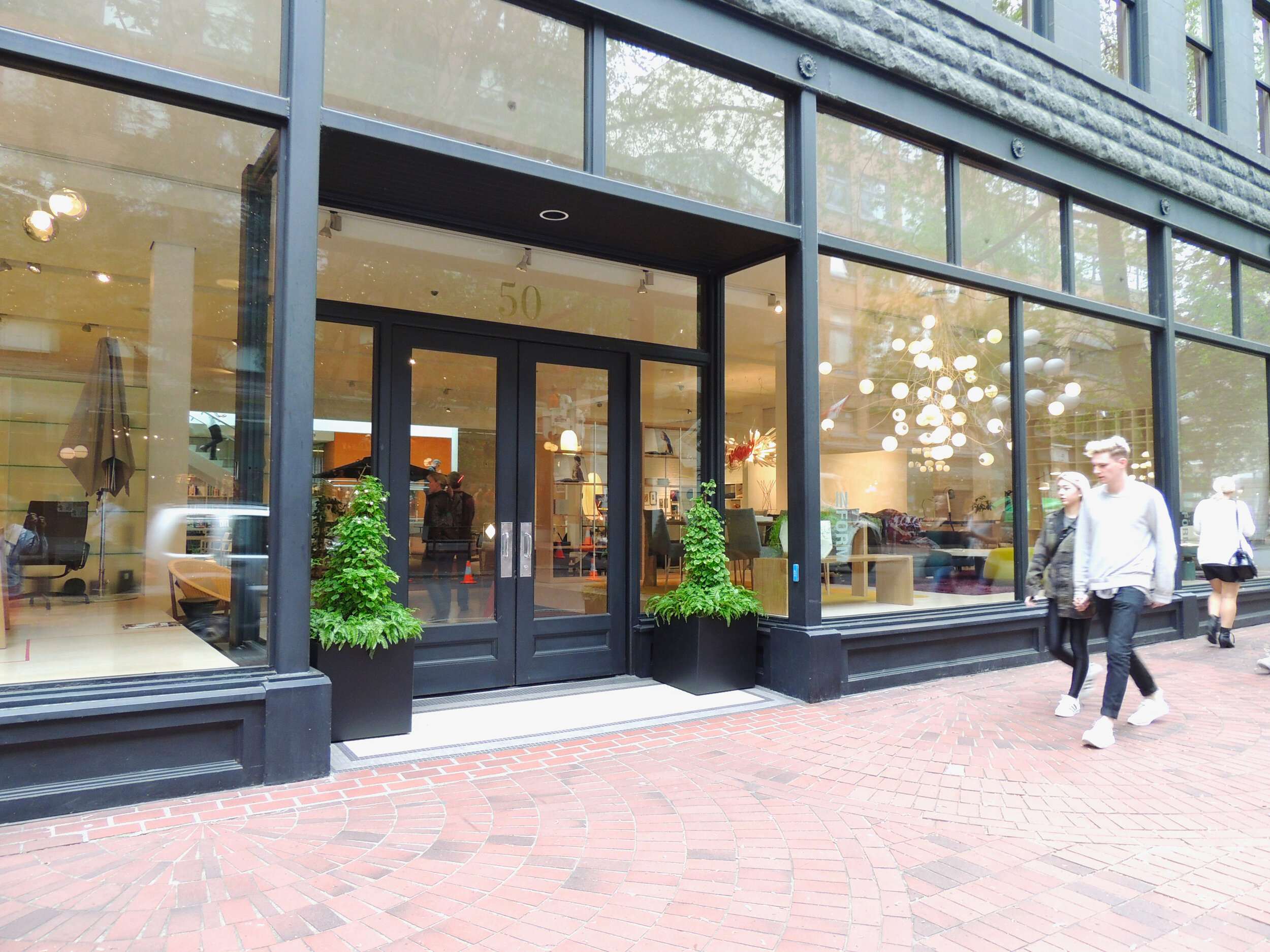 Two black aluminum planters by a store entrance