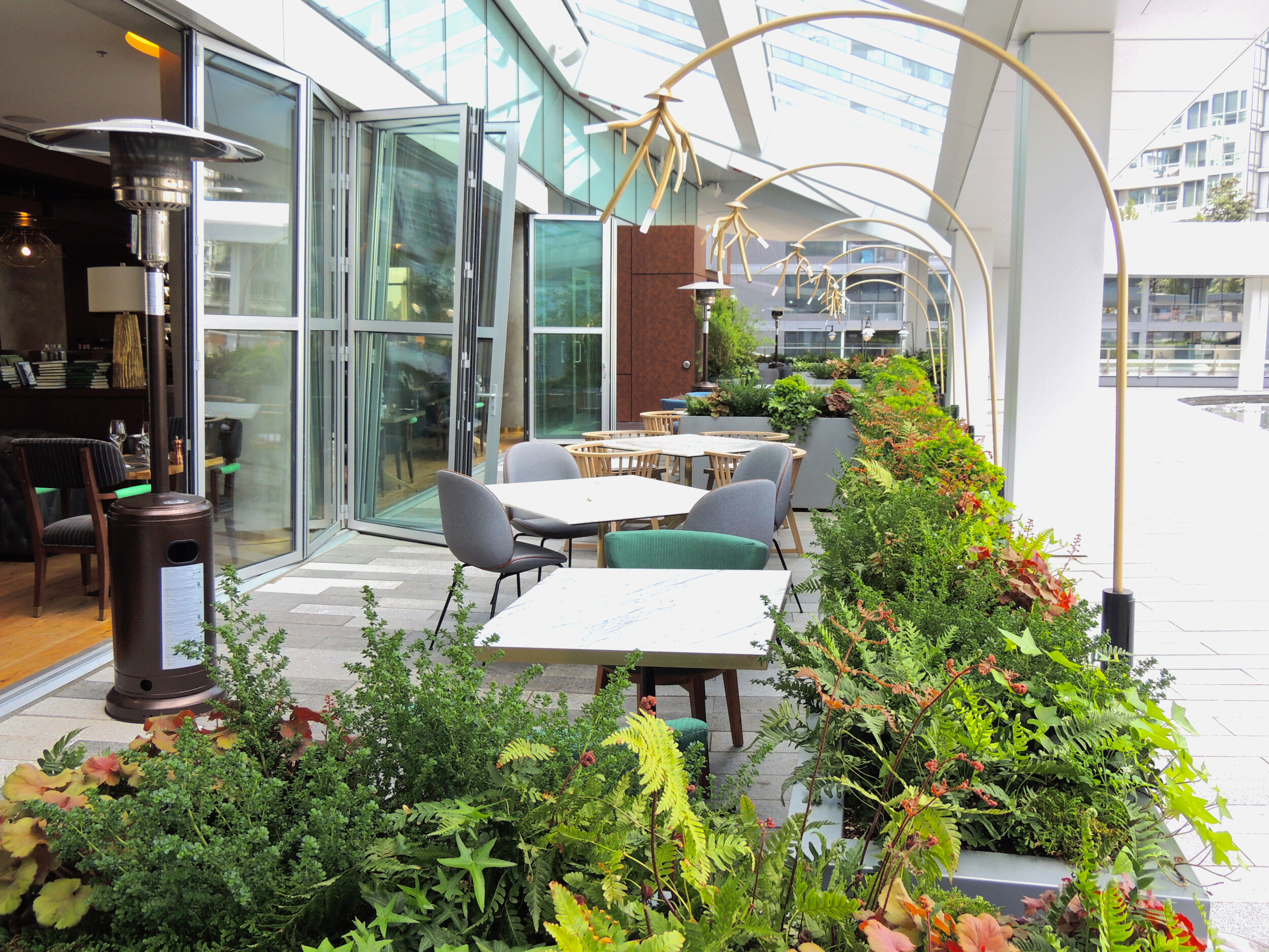 Restaurant patio surrounded by partitions aluminum planters by Object Outdoors