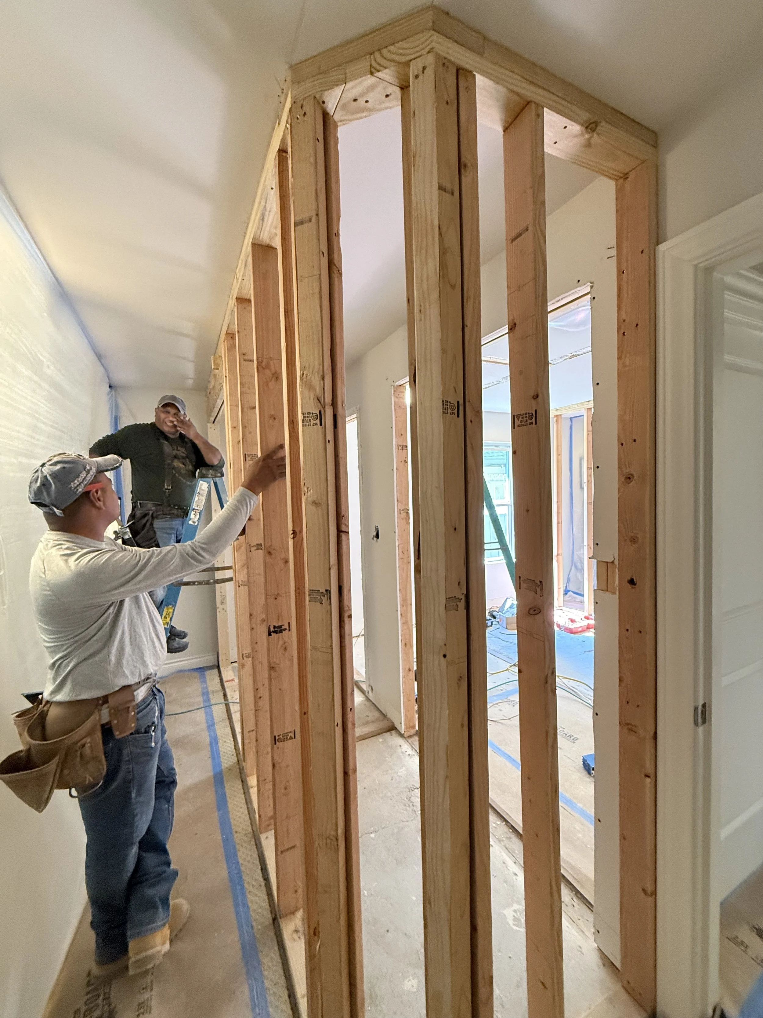 Construction workers installing a new wall frame inside a house.