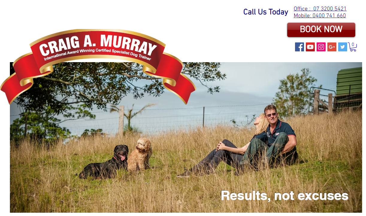 A man and woman sitting on grass in a field, with two dogs, one black and one beige, beside them. The man is smiling and wearing sunglasses, while the woman appears to be resting with her head on his shoulder. There is a tree and a fence in the background. Text on the image says 'Results, not excuses' and a banner reading 'Craig A. Murray, International Award Winning Certified Specialist Dog Trainer' at the top.
