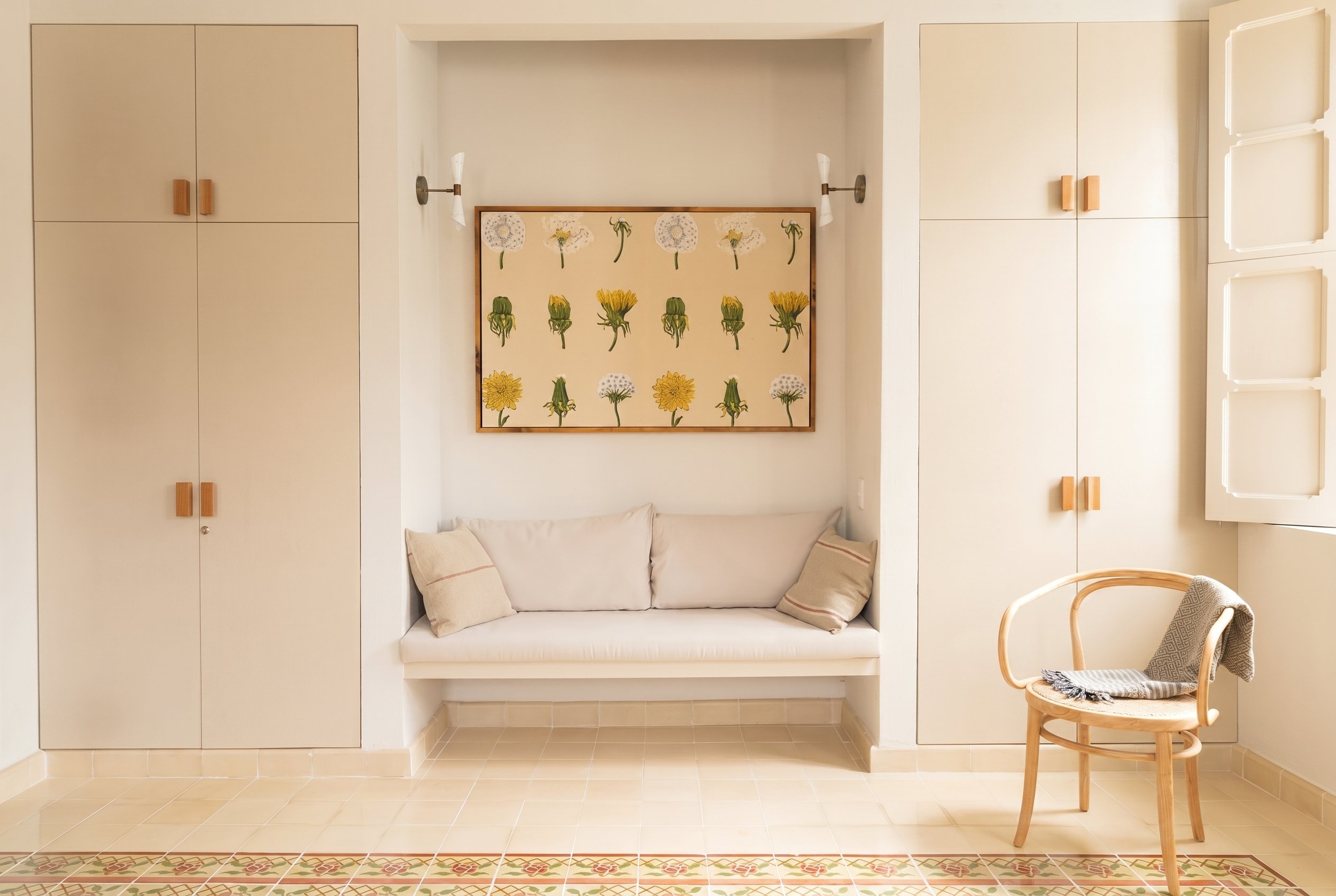 Custom built-in closet and floating bench with framed vintage fabric and restored pasta tiles at Casa Goliana by Laseu Studio