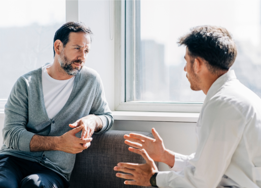 two-men-sitting-together-in-calm-focused-counseling-session-engaged-in-serious-conversation-during-mens-therapy-paraclete-counseling-center