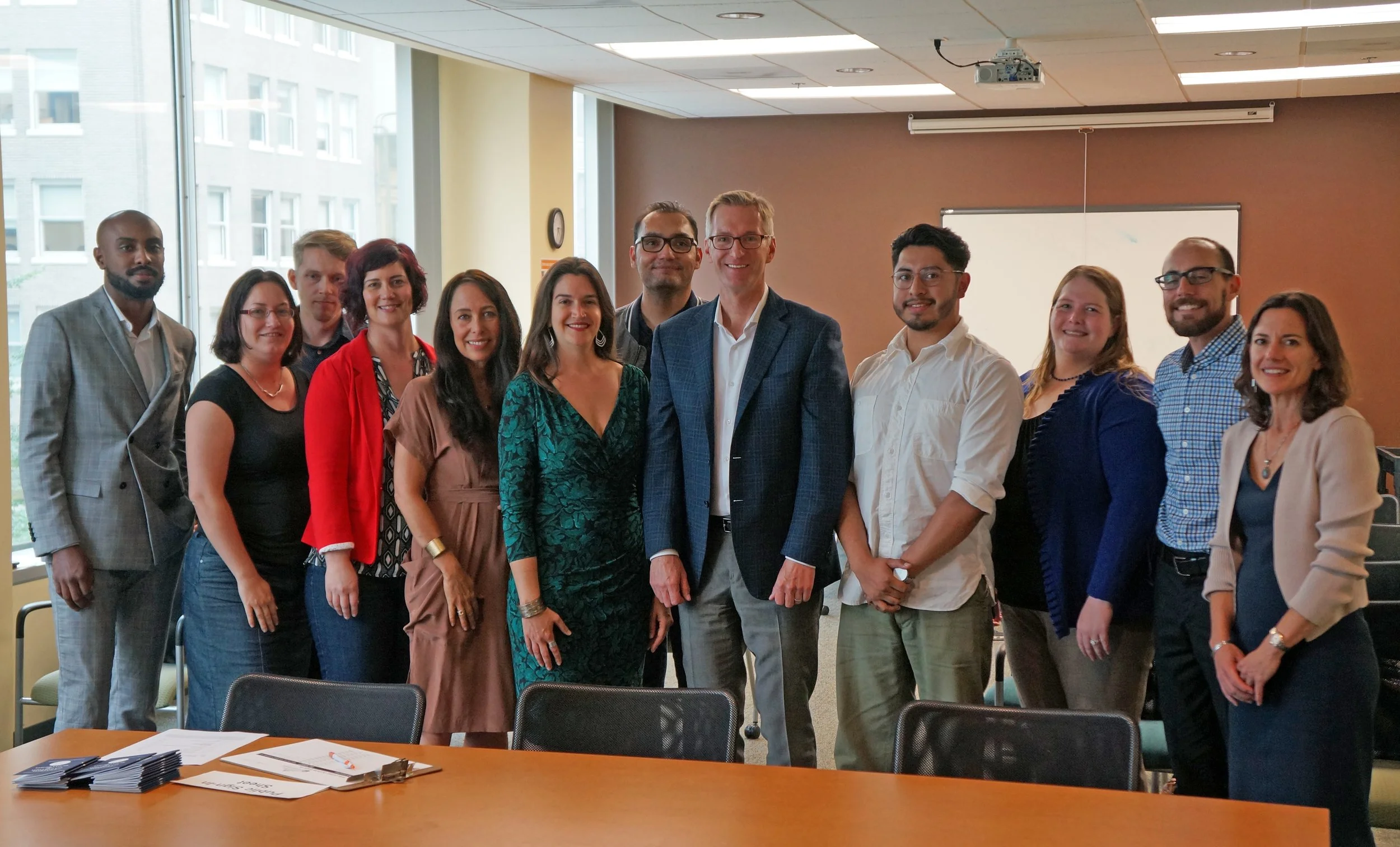 Group of diverse professionals standing together in a conference room, smiling for the photo.