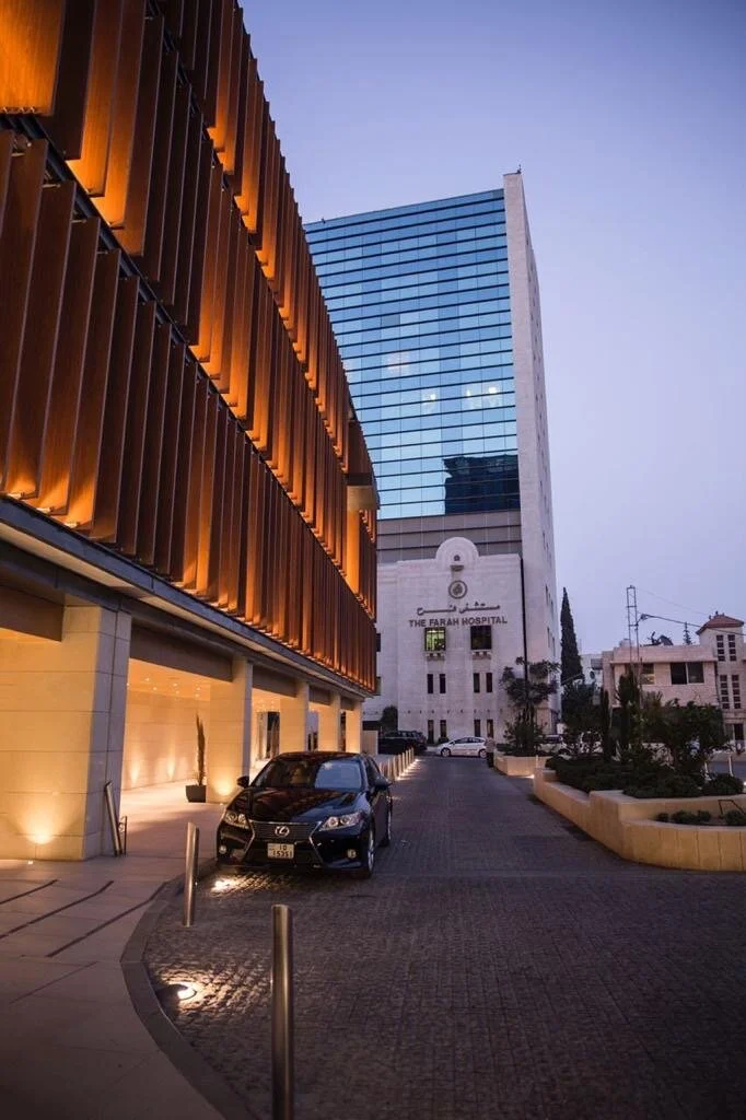 Farah general hospital street pathway main entrance evening shot with lights. Wood vertical louvers covering windows parked car near entryway sunset.