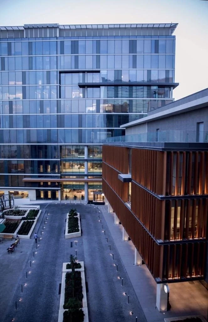 Farah general hospital overview street entrance. Trees and vertical louvers covering windows afternoon lighting. Hospital main facade. L-shaped hospital with entryway.