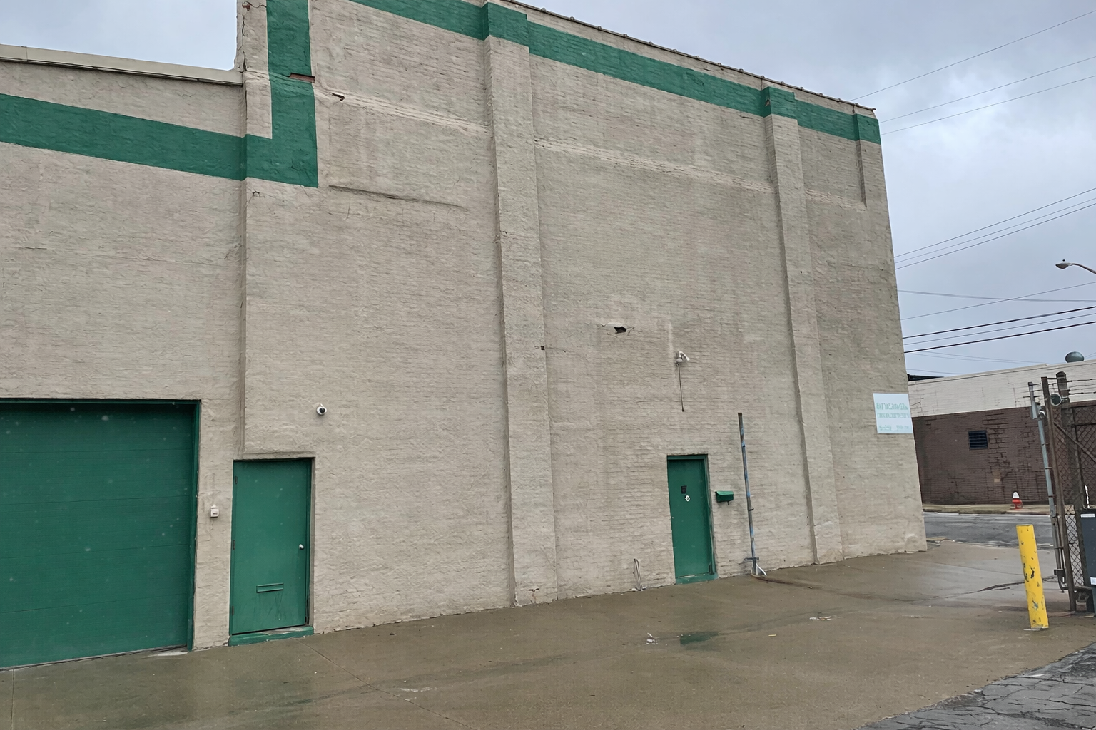 Beige industrial building with green doors.png
