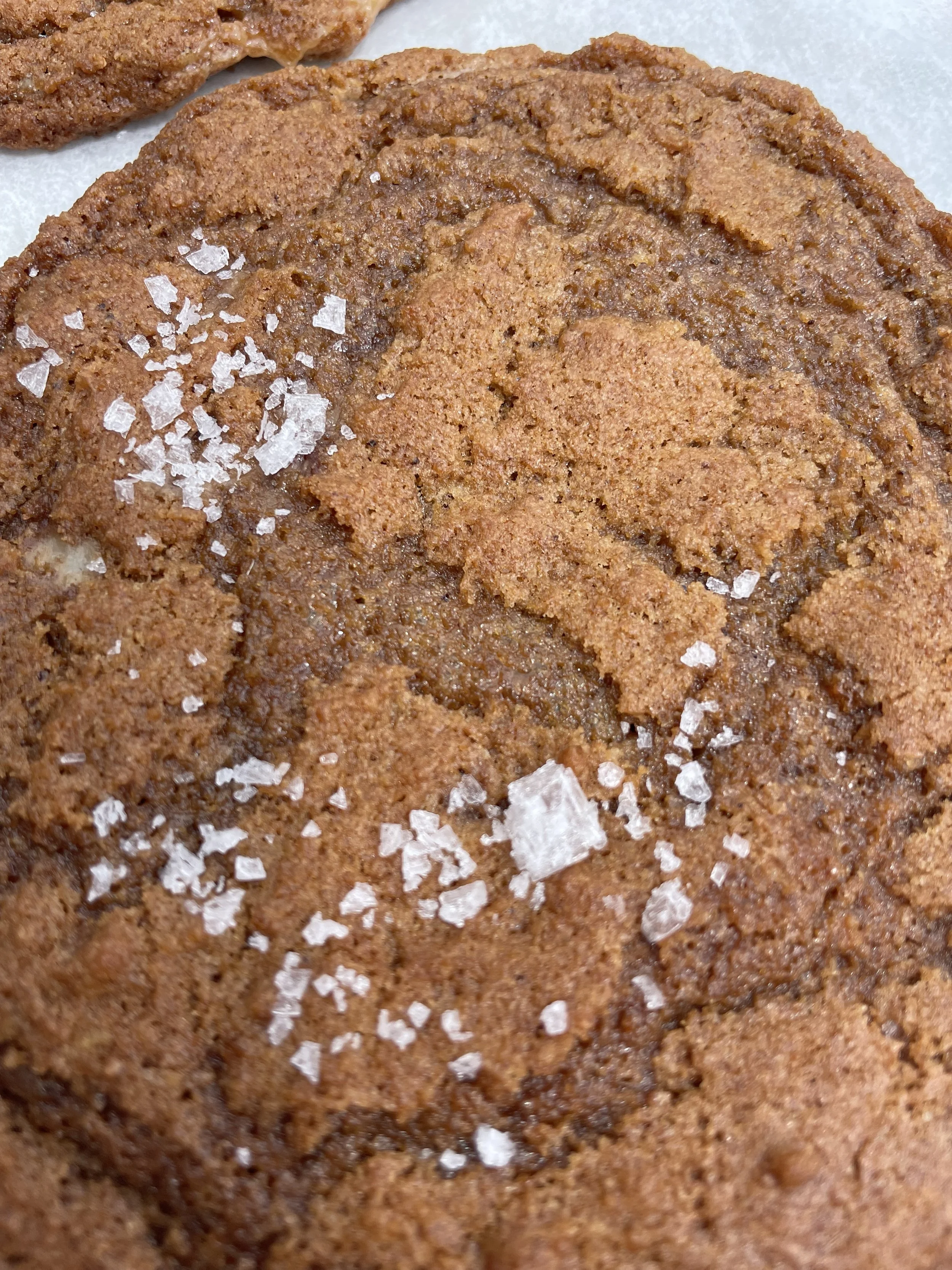 Close-up of a salted chocolate chip cookie with visible salt crystals on top.