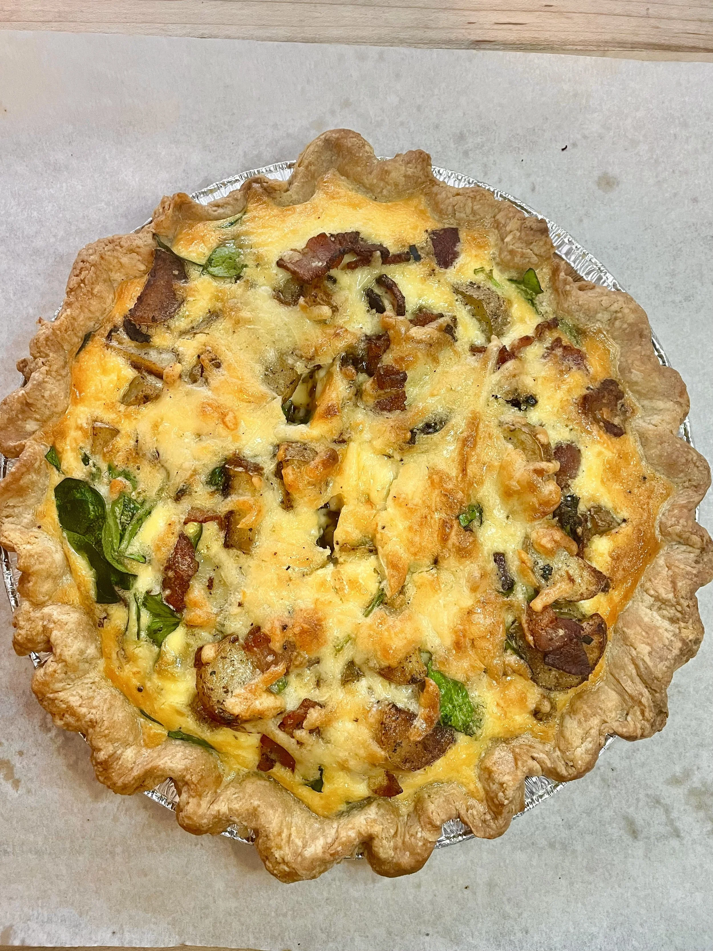 quiche with a flaky crust, cheese, potatoes, spinach.