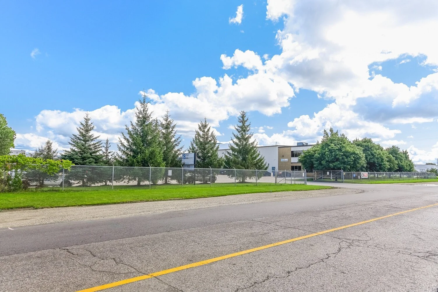 Paved road with a yellow centre line and evergreen trees beside 455 Silvercreek Parkway North