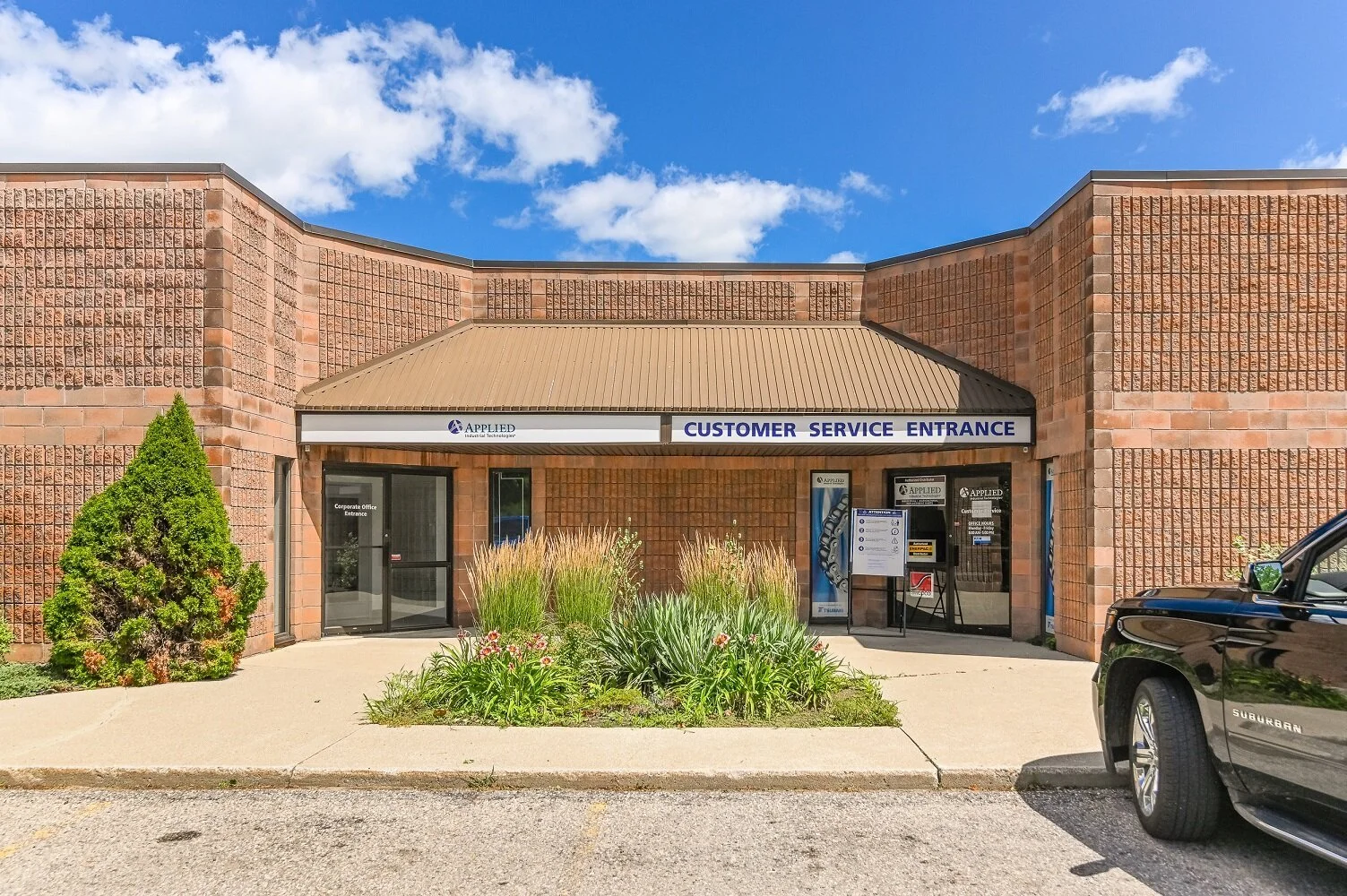 Customer service entrance with an awning, evergreen shrub and walkway at 335-337 Sovereign Road