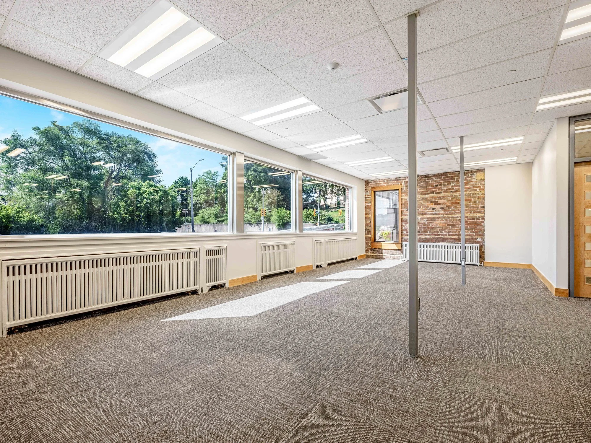 Open office floor with large windows and an exposed brick wall at 8 Macdonell Street, Unit 200A, Guelph