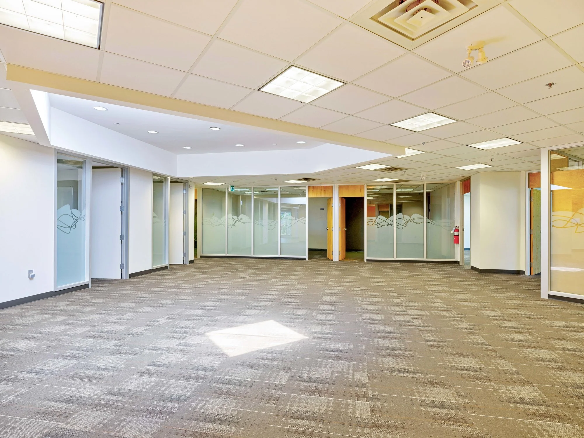 Large open office space with glass-fronted offices along the wall