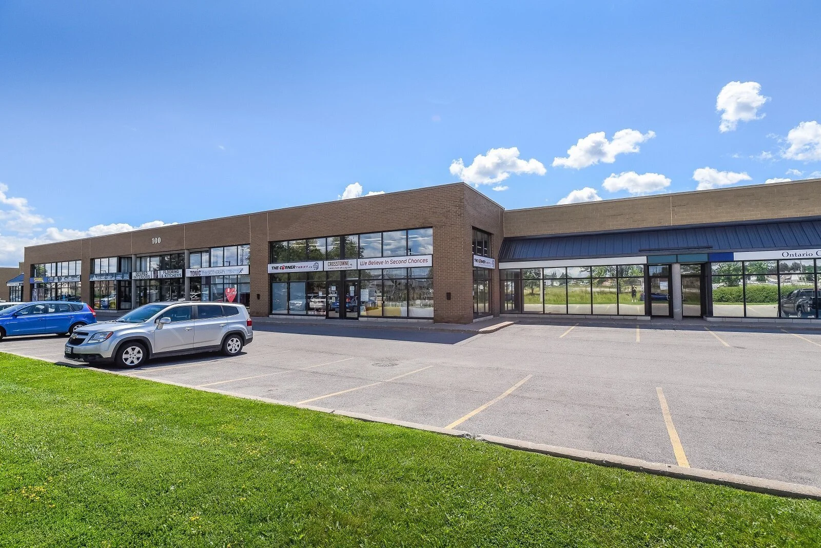 Storefronts with lawn and parked cars at 100 Nipissing Road, Milton