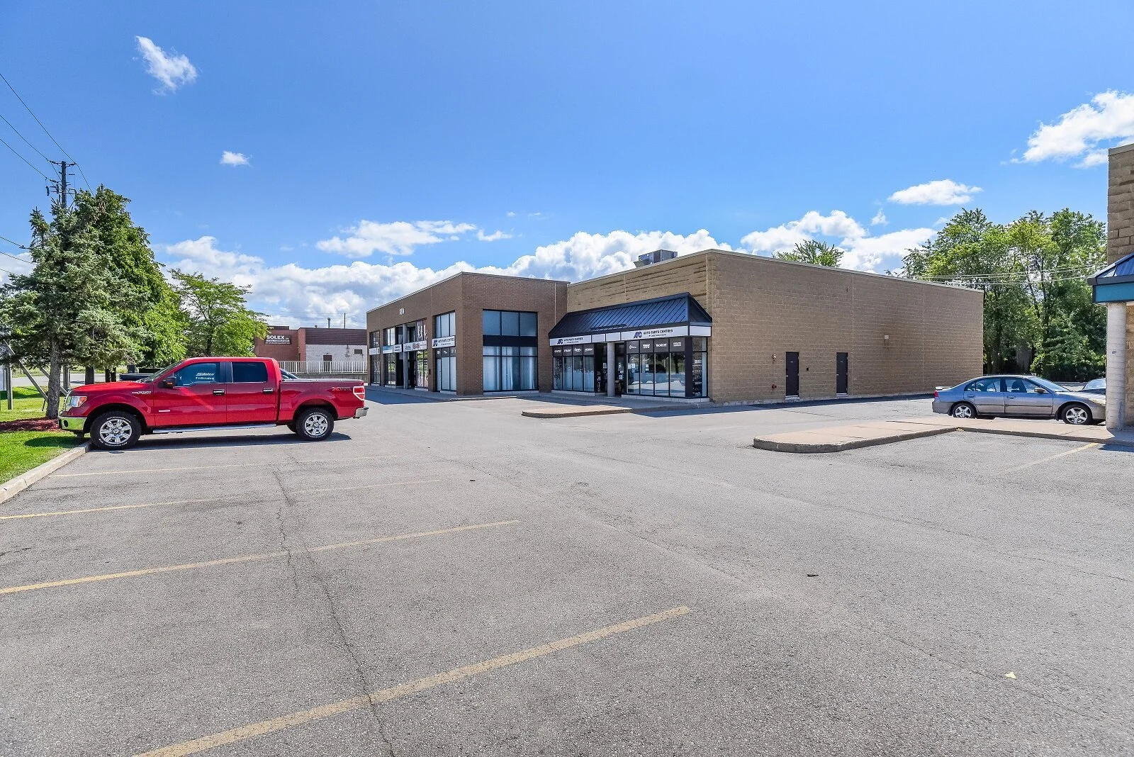 Plaza storefronts across the parking lot at 180 Nipissing Road, Milton