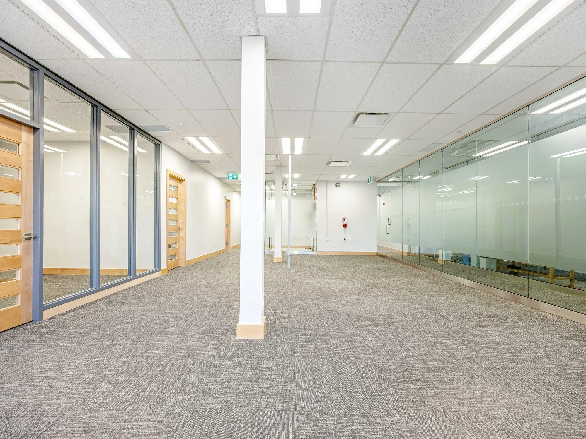 Open office floor with a white column and a row of glass-walled offices with wood doors at 8 Macdonell Street, Unit 200A, Guelph