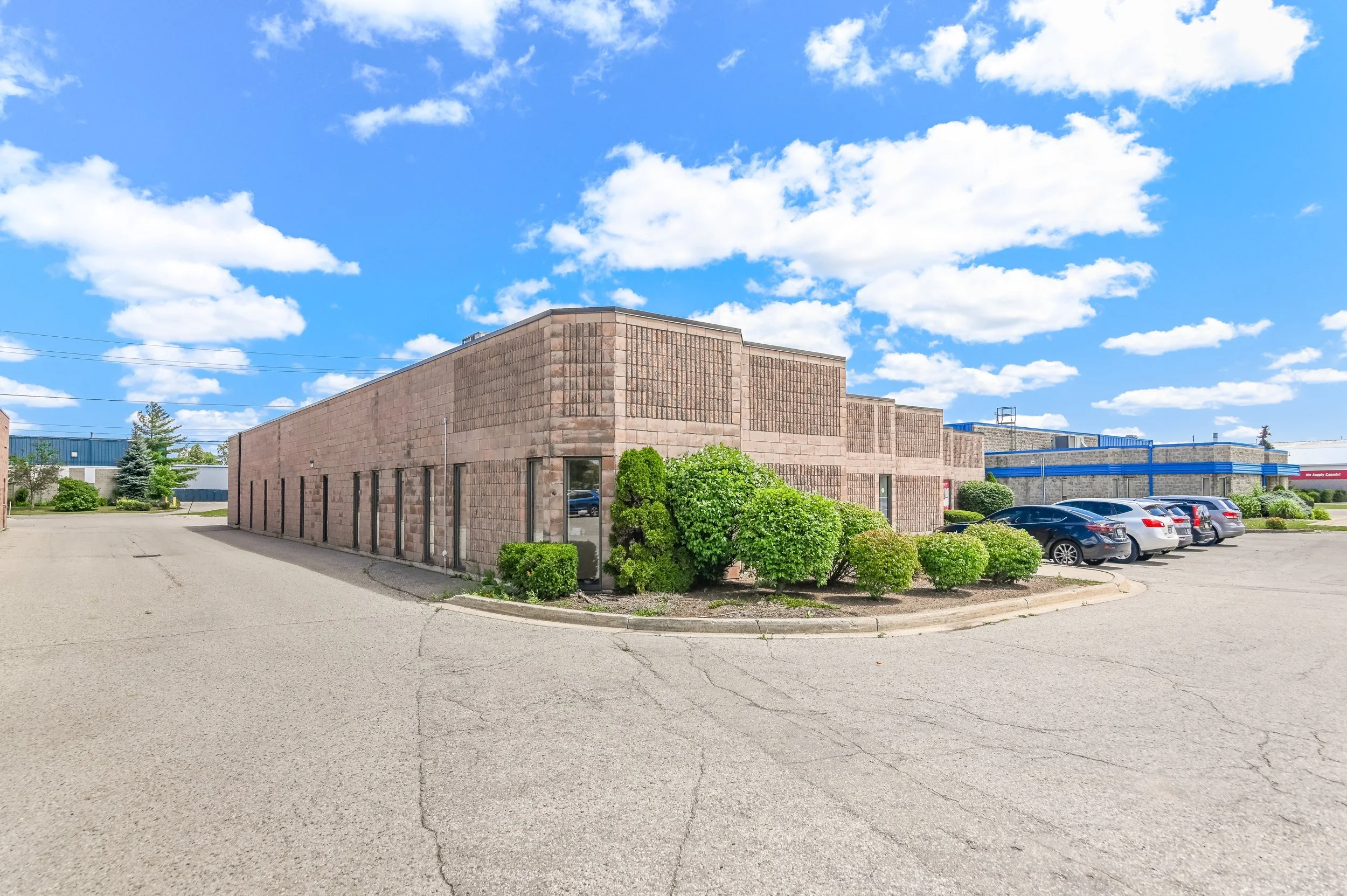 Brick building corner with landscaping and parked cars at 335 Sovereign Road