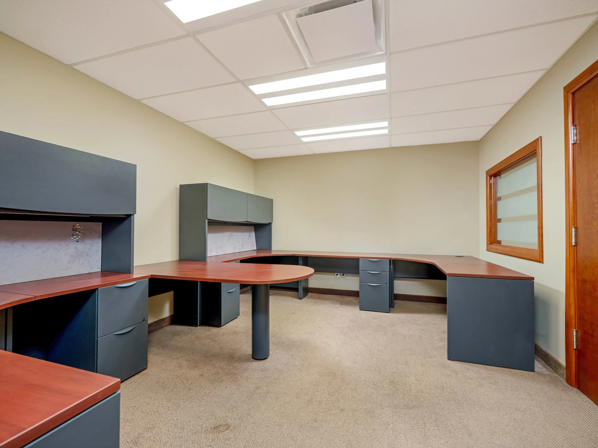 Open office with gray workstations and red-topped desks