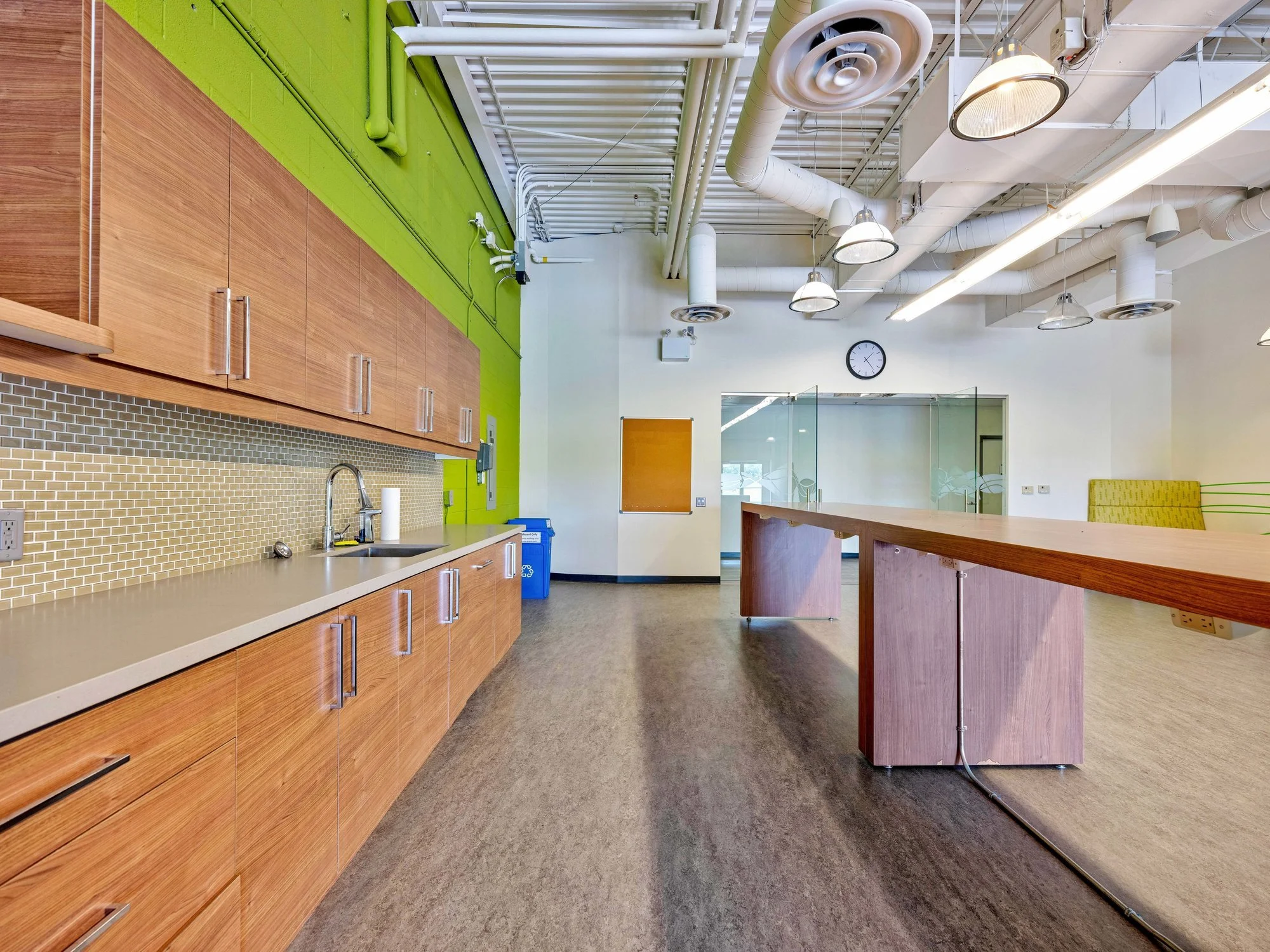Kitchen and cafeteria area with wood cabinetry and a green accent wall