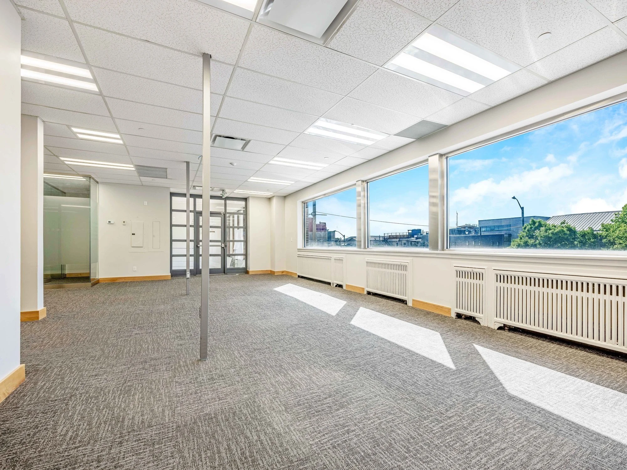 Open office floor with exposed ceiling lights and a long run of windows at 8 Macdonell Street, Unit 200A, Guelph