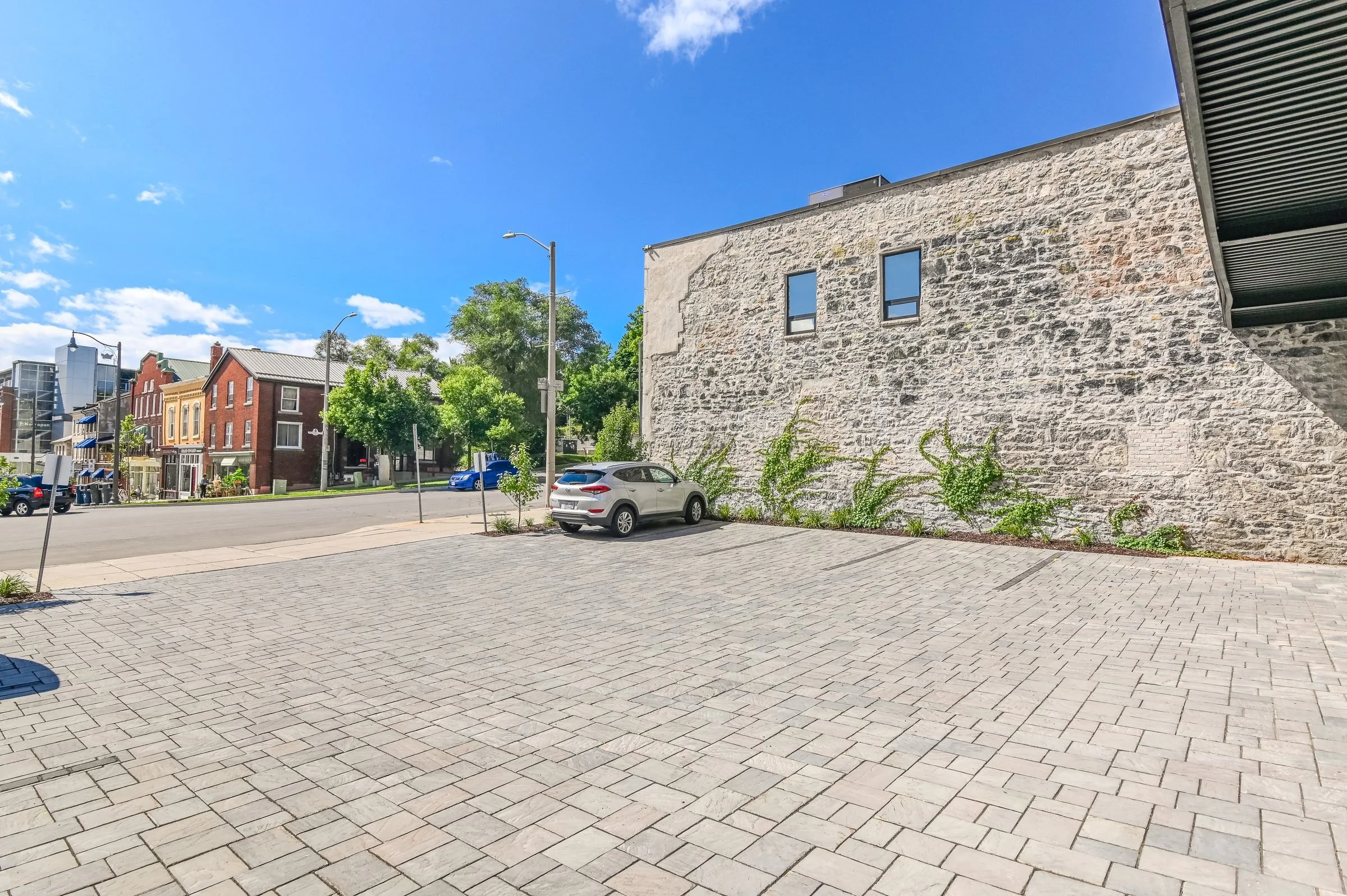 Cobblestone courtyard and stone wall at the Guelph Mercury Building, looking toward the street