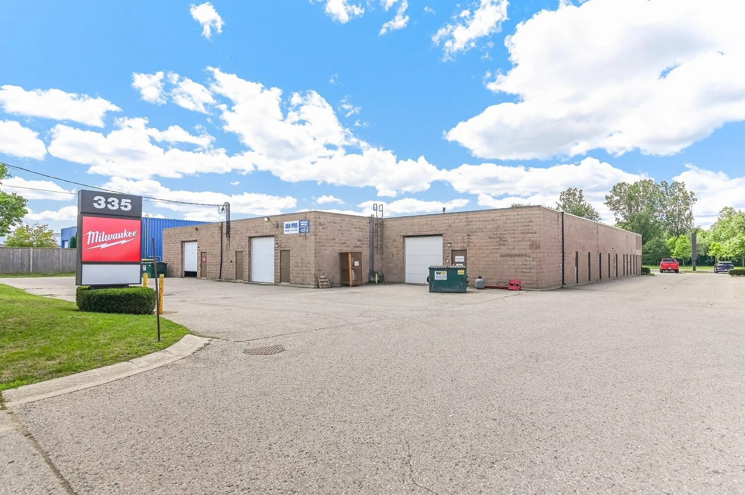 Industrial units with overhead doors and green bins at 335 Sovereign Road