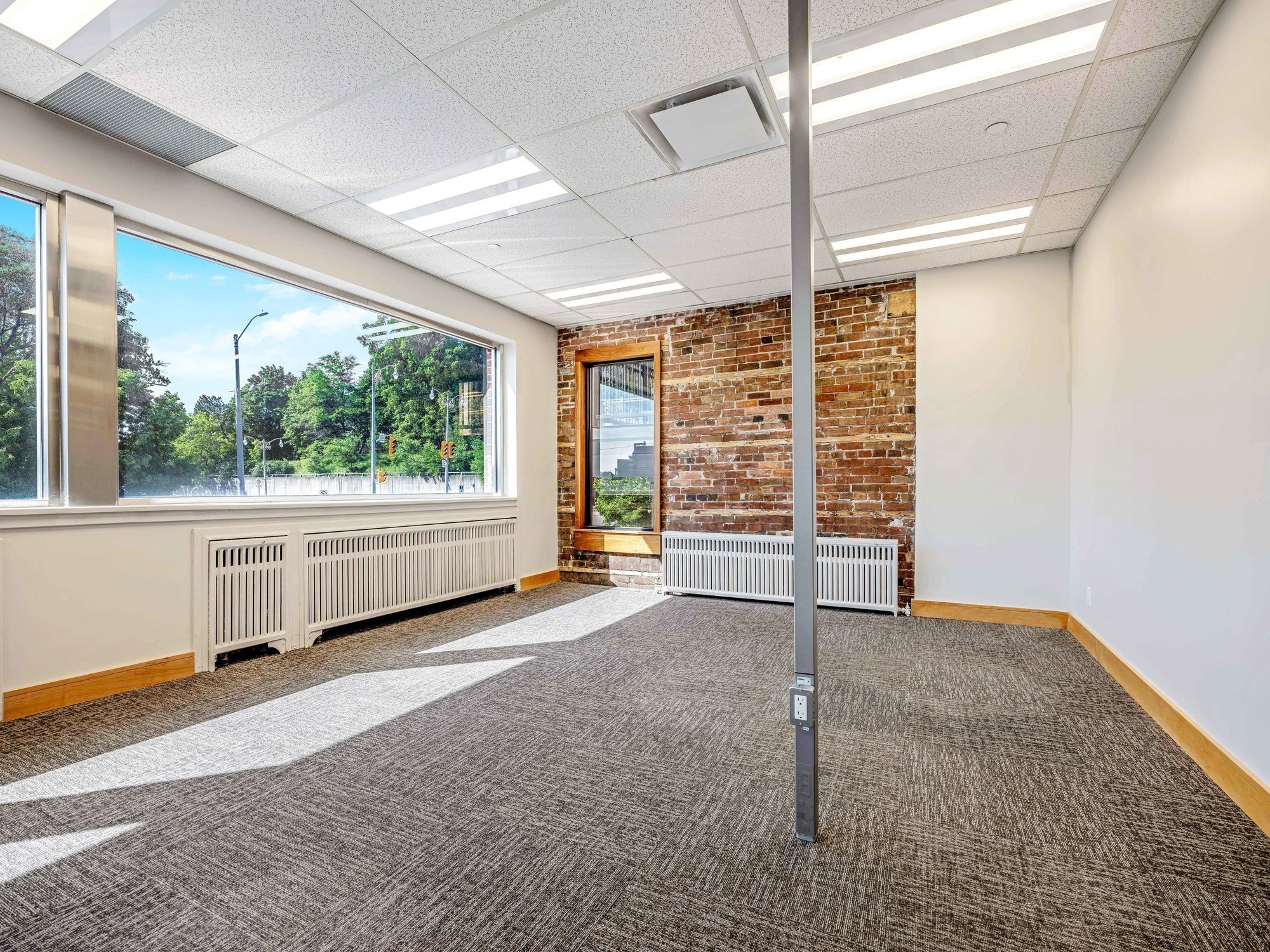 Open second floor office space in Unit 200A with a long window wall, exposed brick and natural light