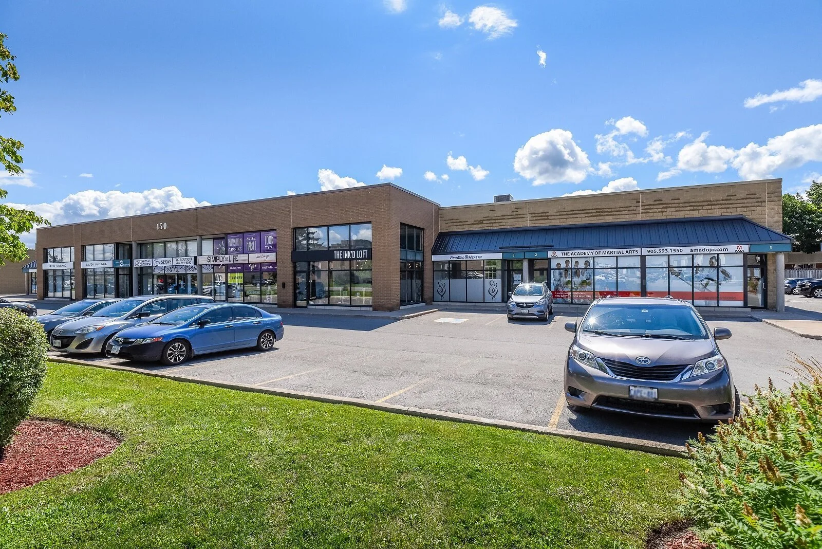 Storefronts with lawn and parked cars at 150 Nipissing Road, Milton