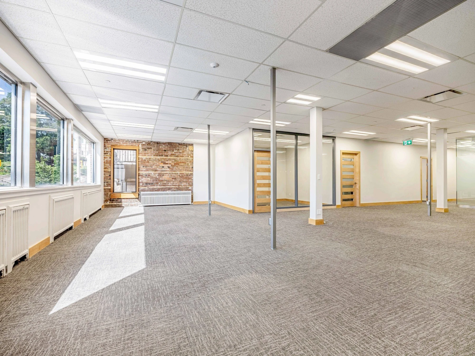Open office floor with support columns and a brick wall at the far end at 8 Macdonell Street, Unit 200A, Guelph