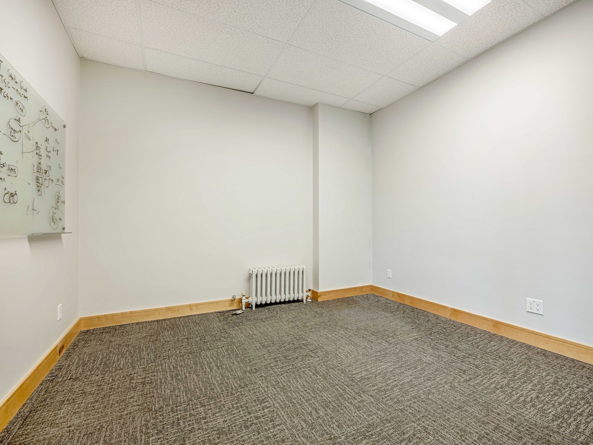 Empty private office with a radiator and whiteboard wall at 8 Macdonell Street, Unit 200A, Guelph