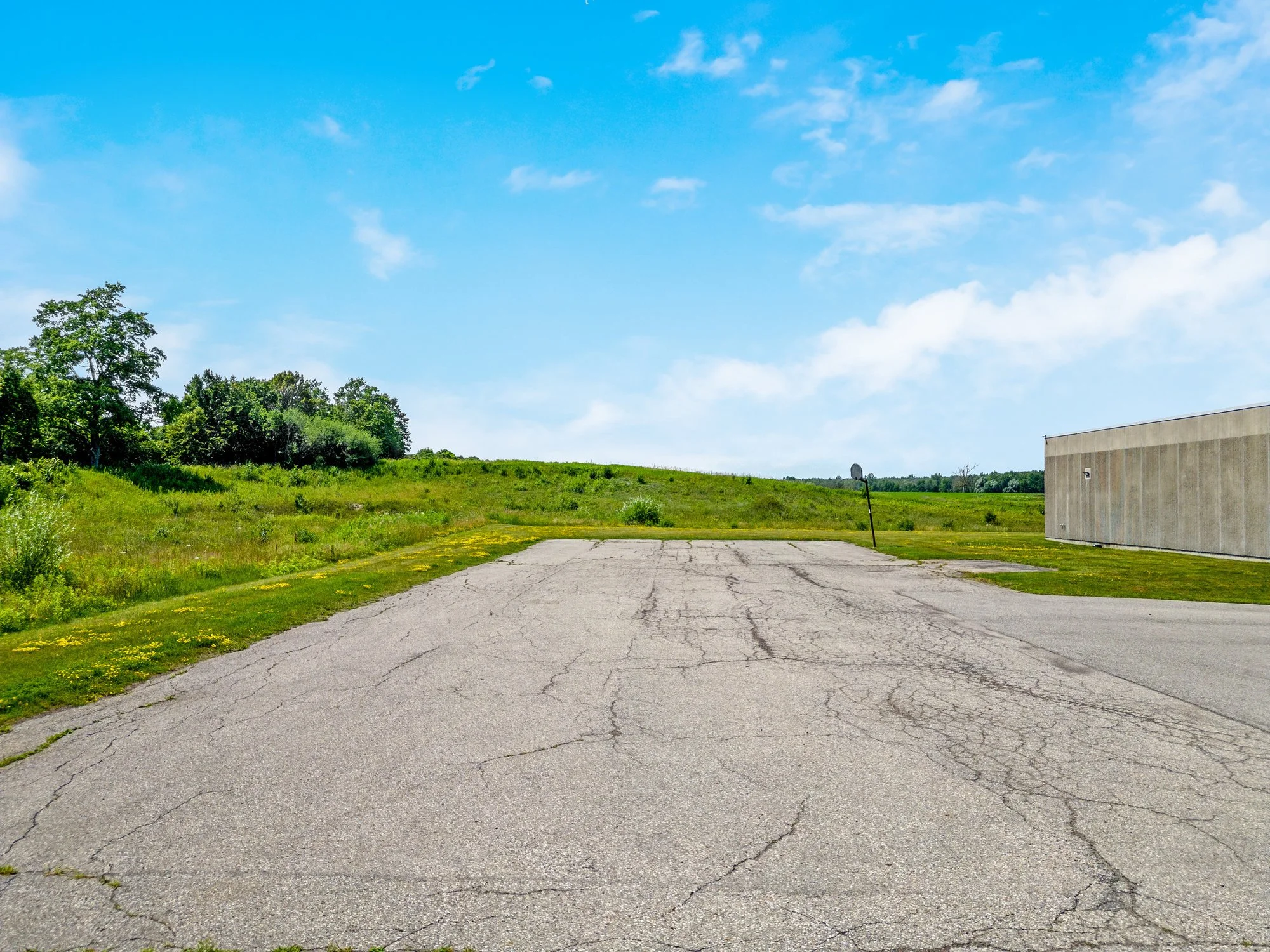 Large paved yard beside the building with open land beyond
