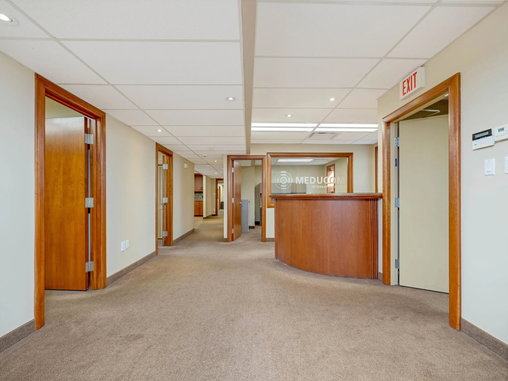 Open reception area with a curved wood desk and wood-framed doors