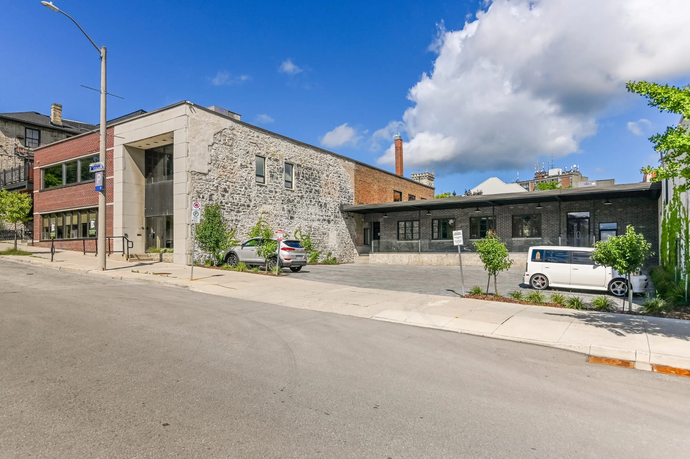 Corner view of the Guelph Mercury Building with its stone wall and low dark wing along the street
