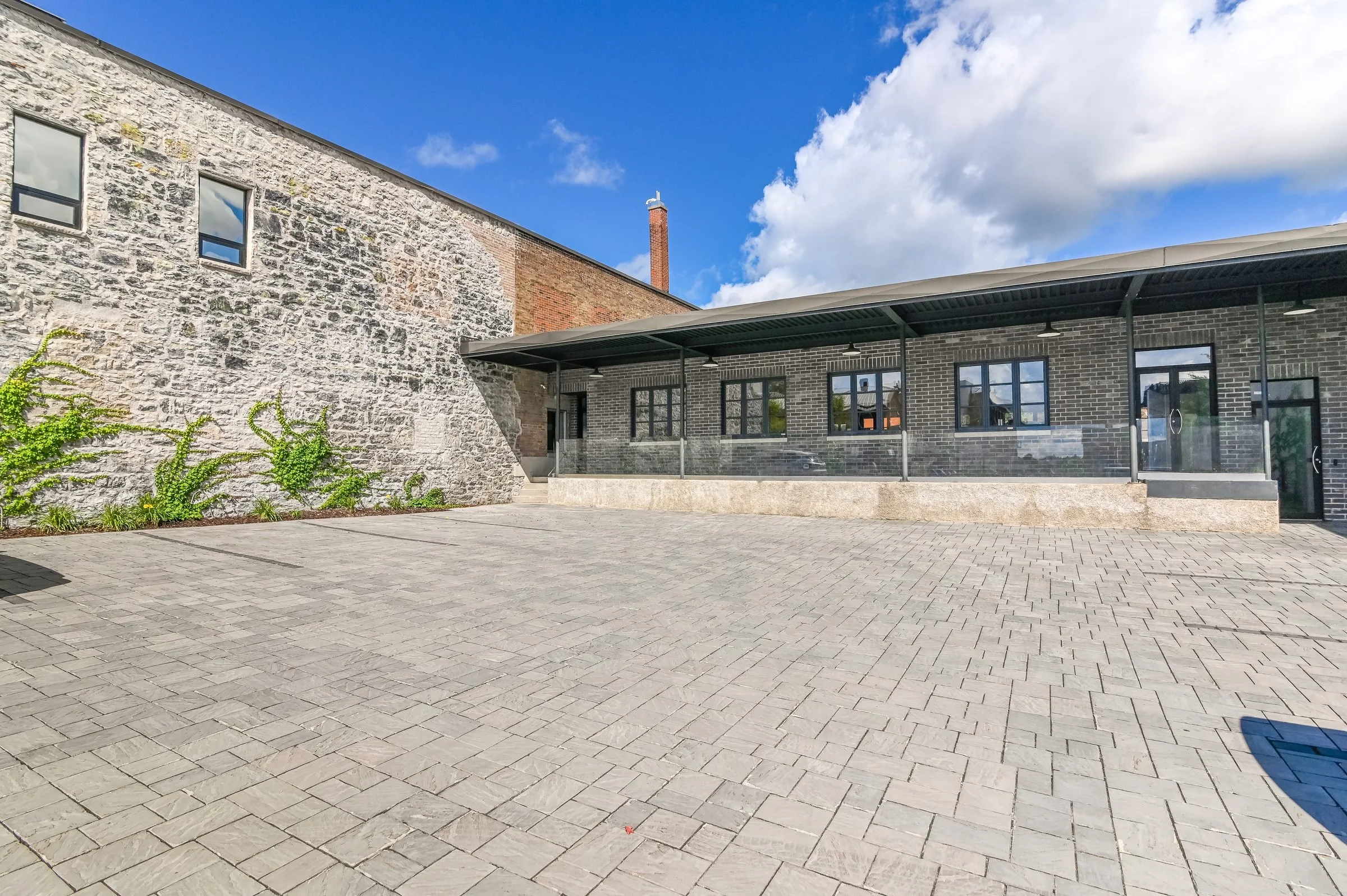 Cobblestone courtyard beside the building's stone wall and dark wing