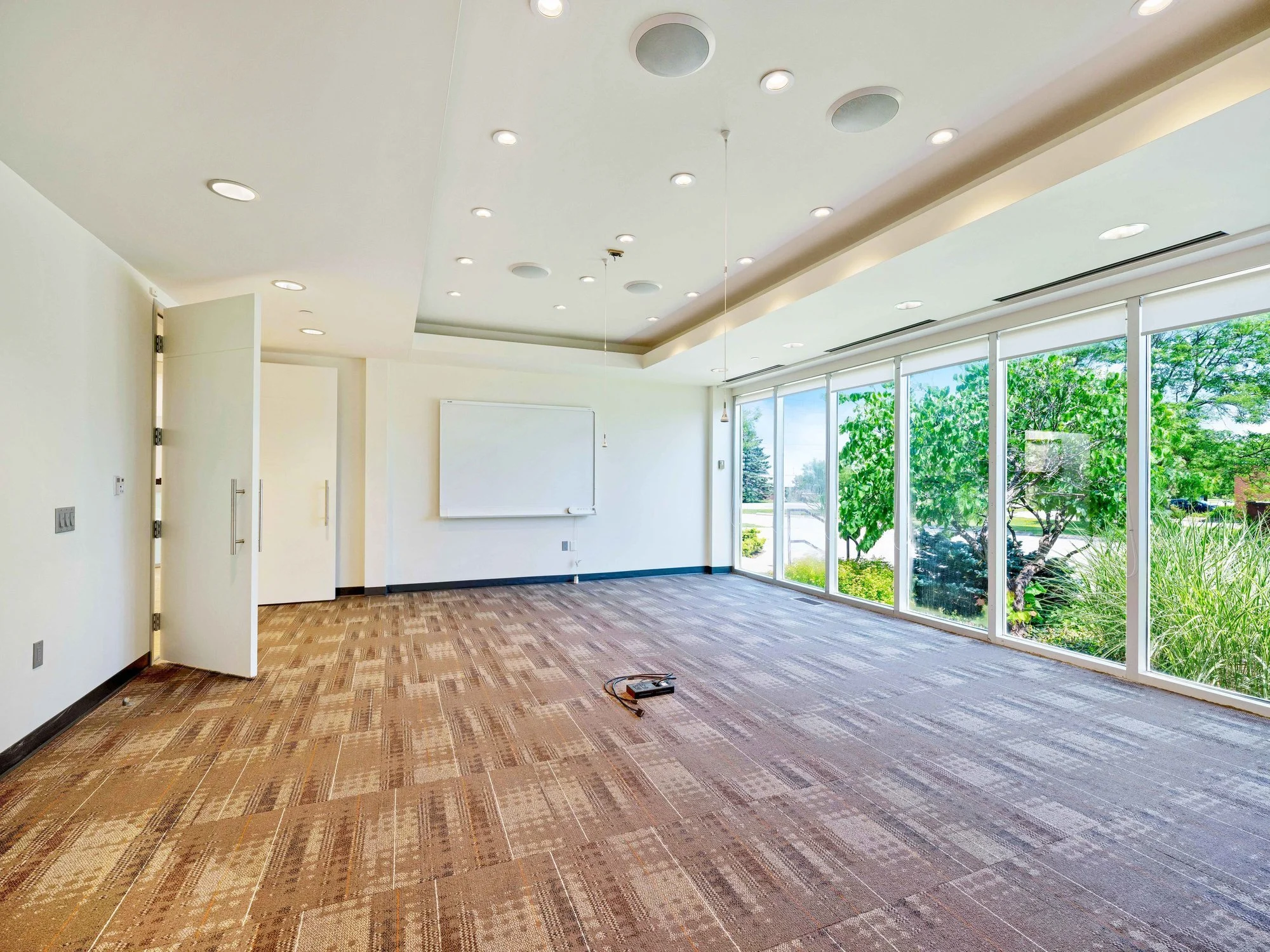 Large room with a wall of windows facing landscaped grounds