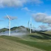 A landscape with multiple wind turbines on rolling green hills under a partly cloudy sky.