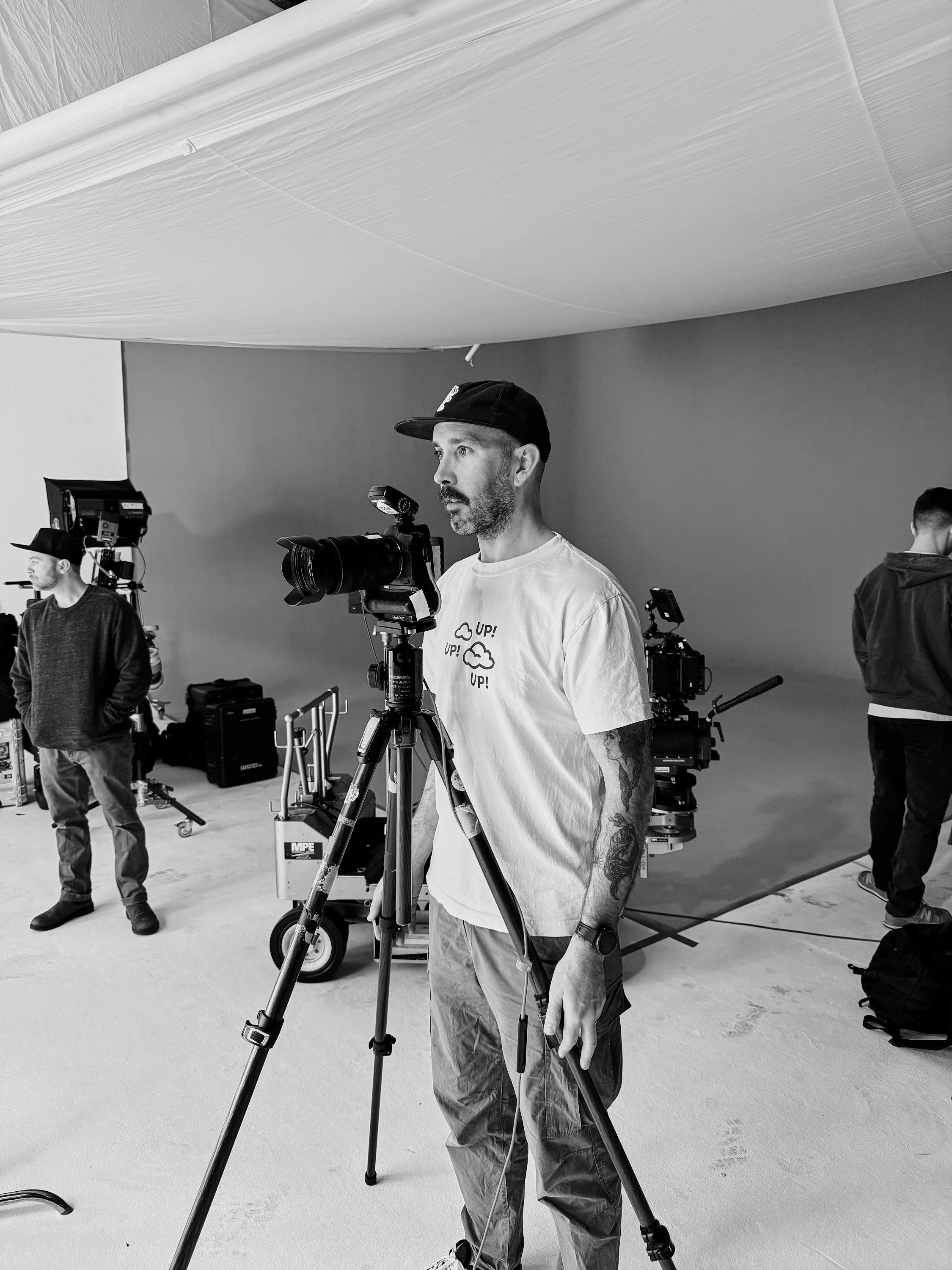 A filmmaking crew sets up equipment on a film set with a green screen and professional cameras.