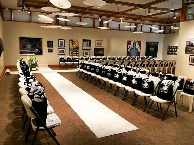 gallery setup with carpets for a runway and chairs on either side for a fashion show