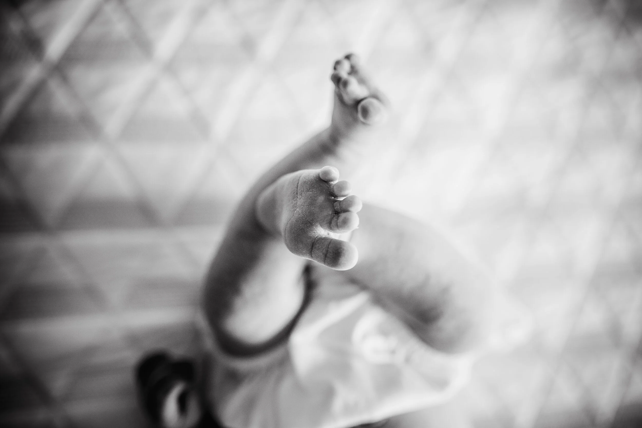 Toes of a newborn baby laying on a bed in Raleigh, North Carolina taken by Jennifer LaGrange, a newborn photographer in Raleigh, North Carolina.