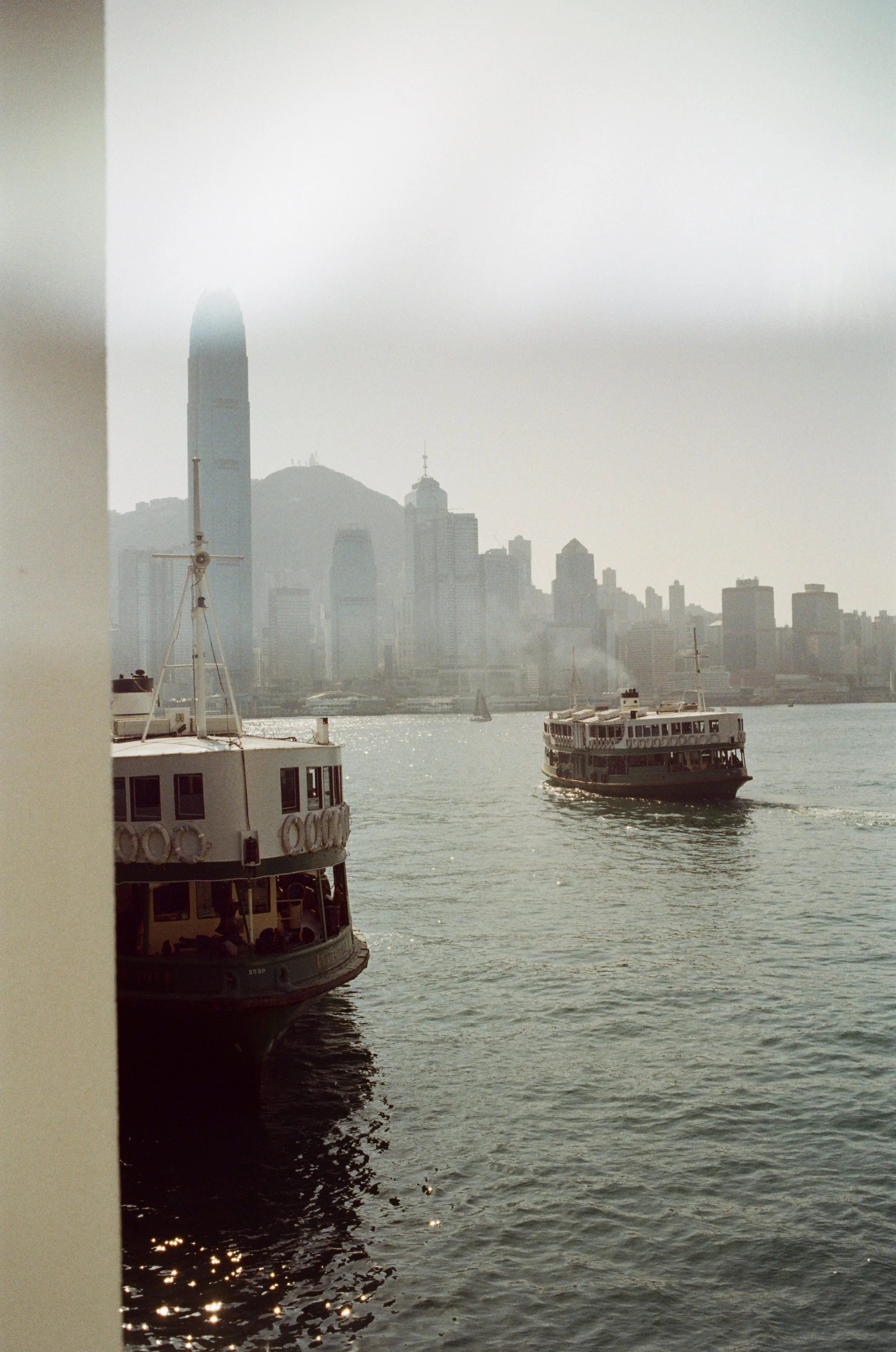 Ferries sailing on the water with a cityscape skyline in the background.