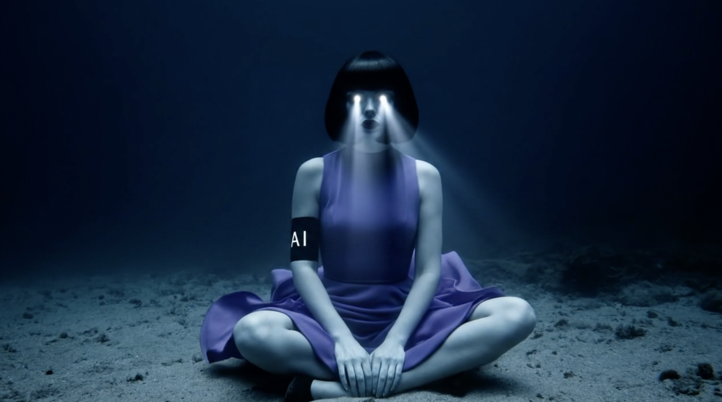 A woman with a bob haircut and a purple dress sits cross-legged on the sand in a dark, empty space. Her eyes emit beams of light, and she has an armband with the letters 'AI' on her upper arm. From the AI short film '404.'
